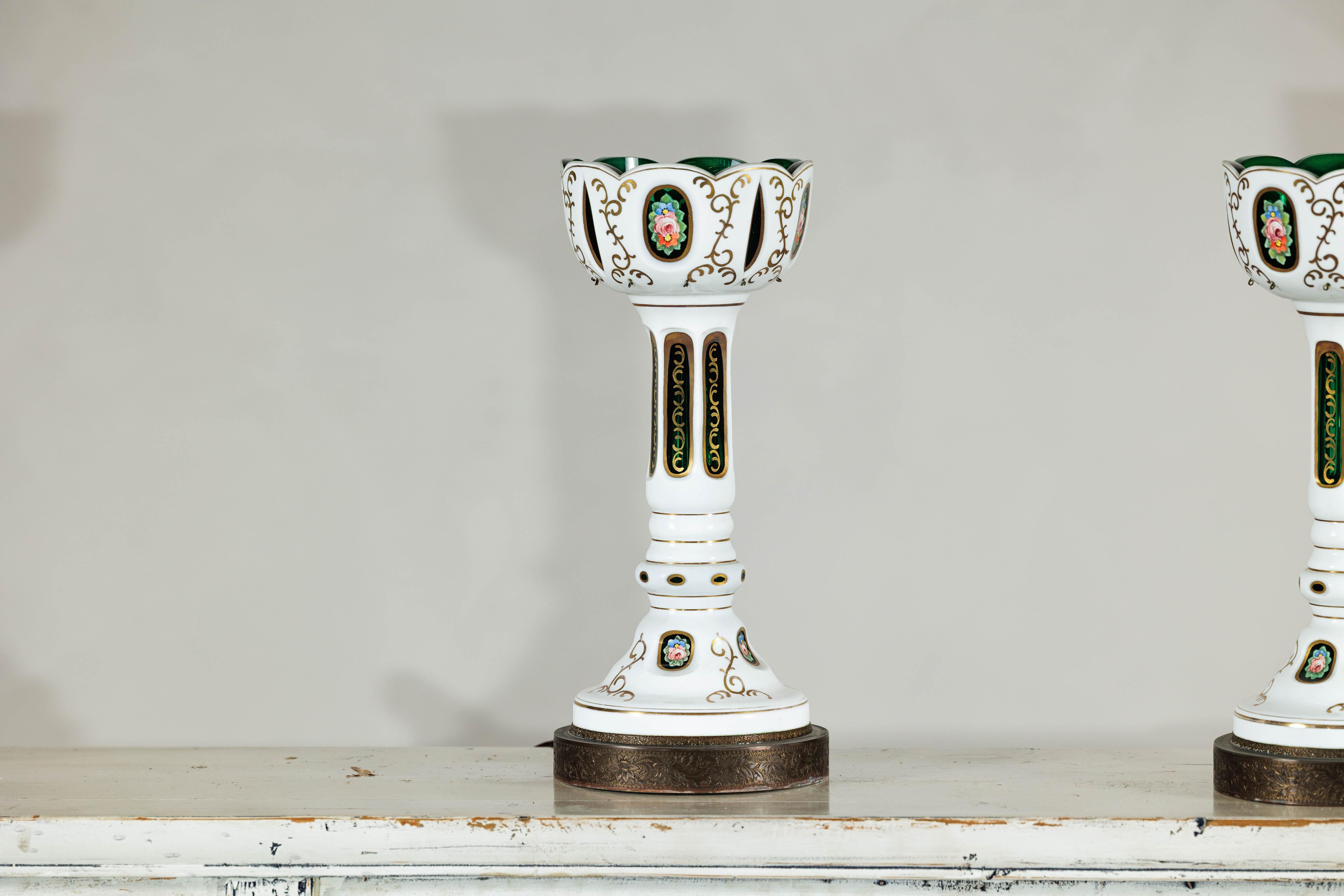 Cette paire de lampes bohémiennes tchèques vintage met en valeur l'élégance de l'art du verre moulé, avec un riche jeu de superposition entre le blanc et le vert émeraude profond taillé dans le verre clair. Chaque lampe est ornée d'une série de