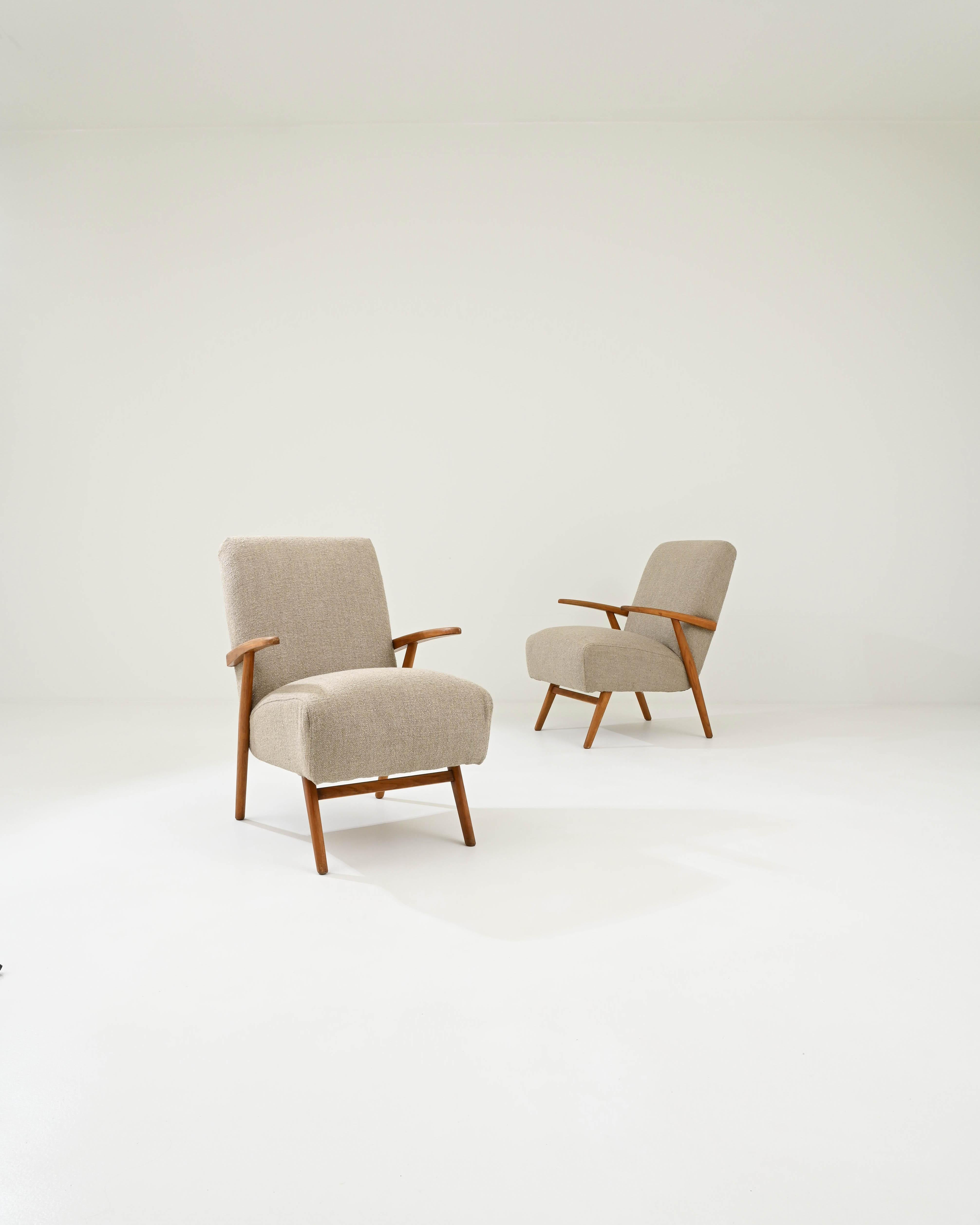 Designed in Czechia circa 1940, this pair of mid-century modern armchairs flaunts sculptural silhouettes, shaped by angular armrests and splayed legs, adding a dynamic and visually appealing flavor to the pieces. The warm tawny hue of the wood