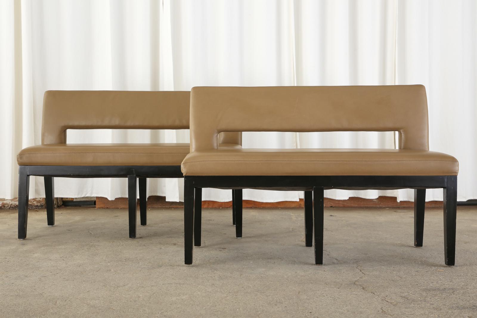 Stylish pair of dining banquette benches or settees designed by Dakota Jackson. The benches feature a hardwood frame with an ebonized lacquer finish. Upholstered with thick leather the frames have a flat black and open design. The seat is supported