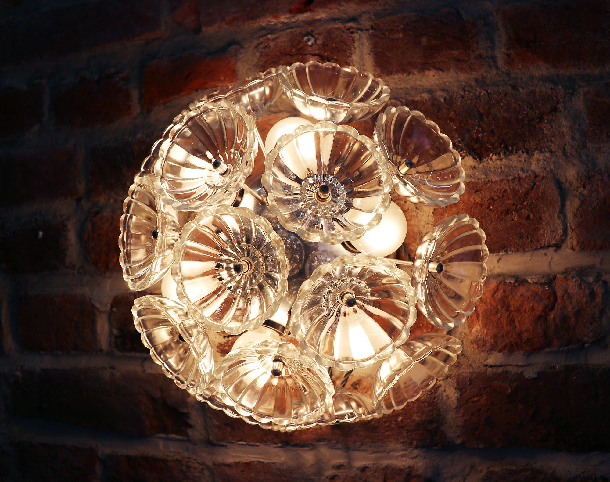 Elegante pareja de apliques de pared y plafones empotrables con forma de diente de león. Cada lámpara tiene diecisiete flores de cristal sobre un marco de metal cromado. Fabricado por VEB, Alemania, en la década de 1960. 

Medidas: diámetro 12,6