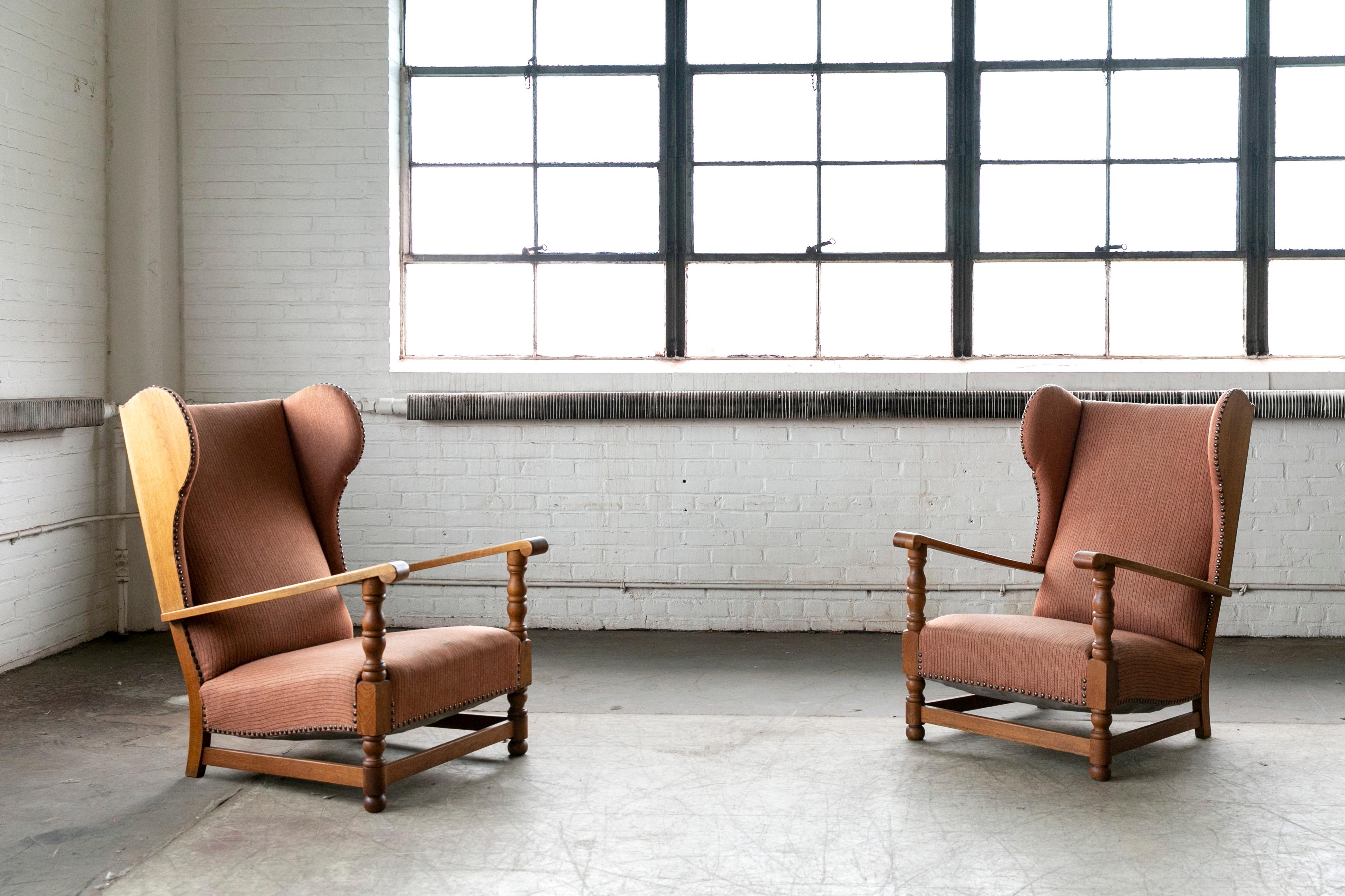 Great example of early Danish midcentury design, circa 1930s wingback chairs in hand carved solid oak with exposed sides and brass nails. Sturdy and strong construction of generous proportions making for a very comfortable chair. Nice patina