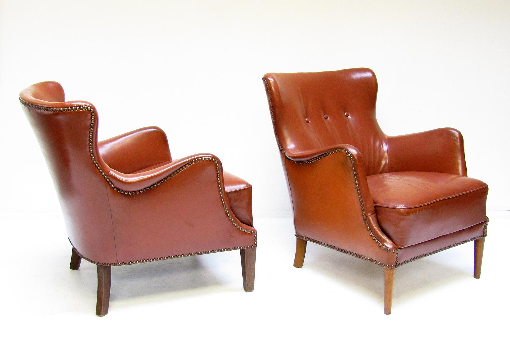 A pair of vintage 1940s Danish lounge or club chairs in original cognac-coloured leather, attributed to Peter Hvidt for Fritz Hansen. 

Of compact dimensions, the sculpted forms are reminiscent of Frits Henningsen's designs. 

These early