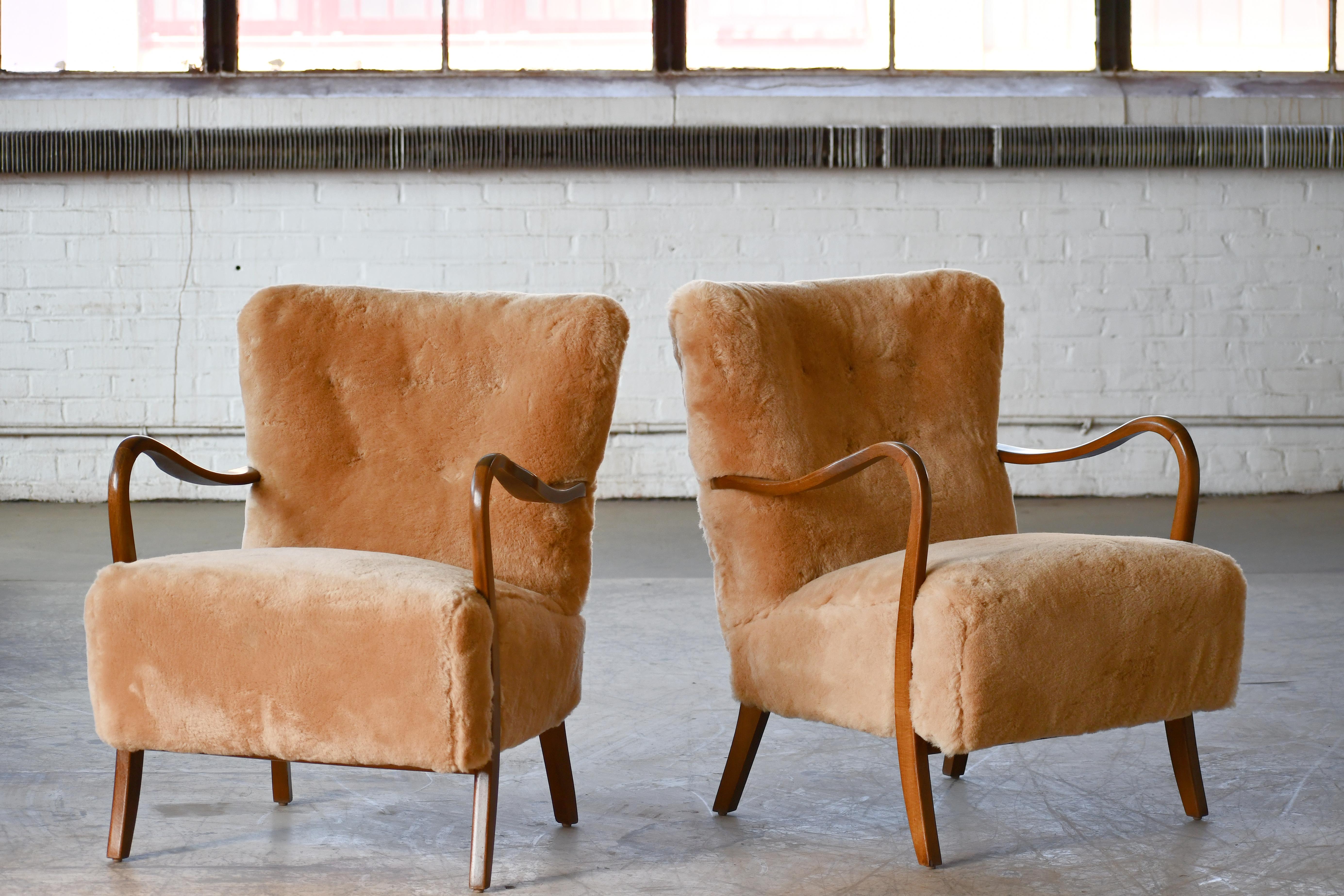 Classic pair of elegant Danish low back armchairs from the 1940s by Alfred Christensen for Slagelse Mobelvaerk with open armrests in beautifully curved stained beech. We have reupholstered them in exuberant amber colored straight fleece sheepskin by