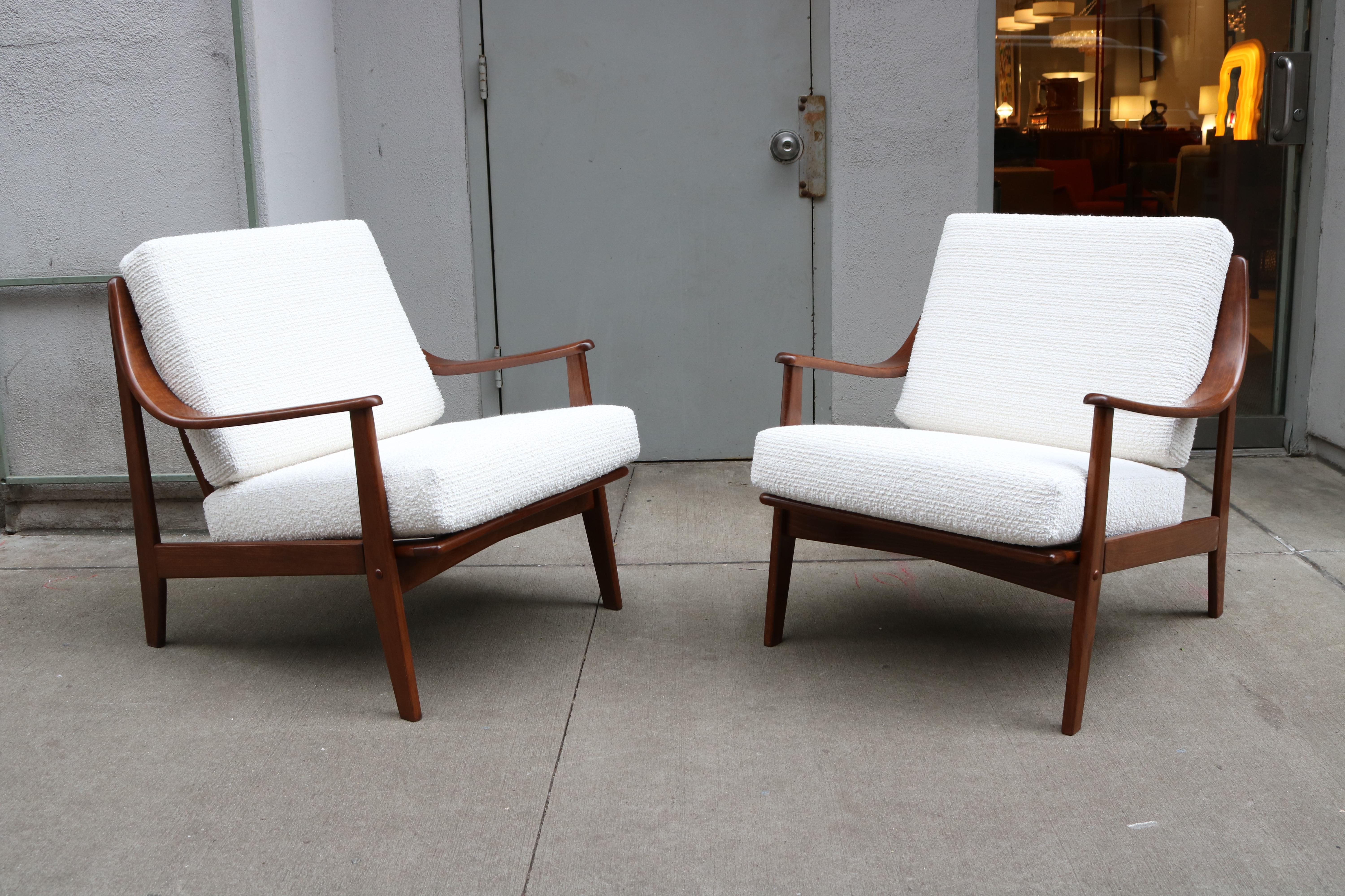 Pair of teak wood armchairs with high curved armrests. 
Designed by Peter Hvidt & Orla Mølgaard-Nielsen for France & Son.
The chairs feature two cushions that have been recovered with a white bouclé fabric.