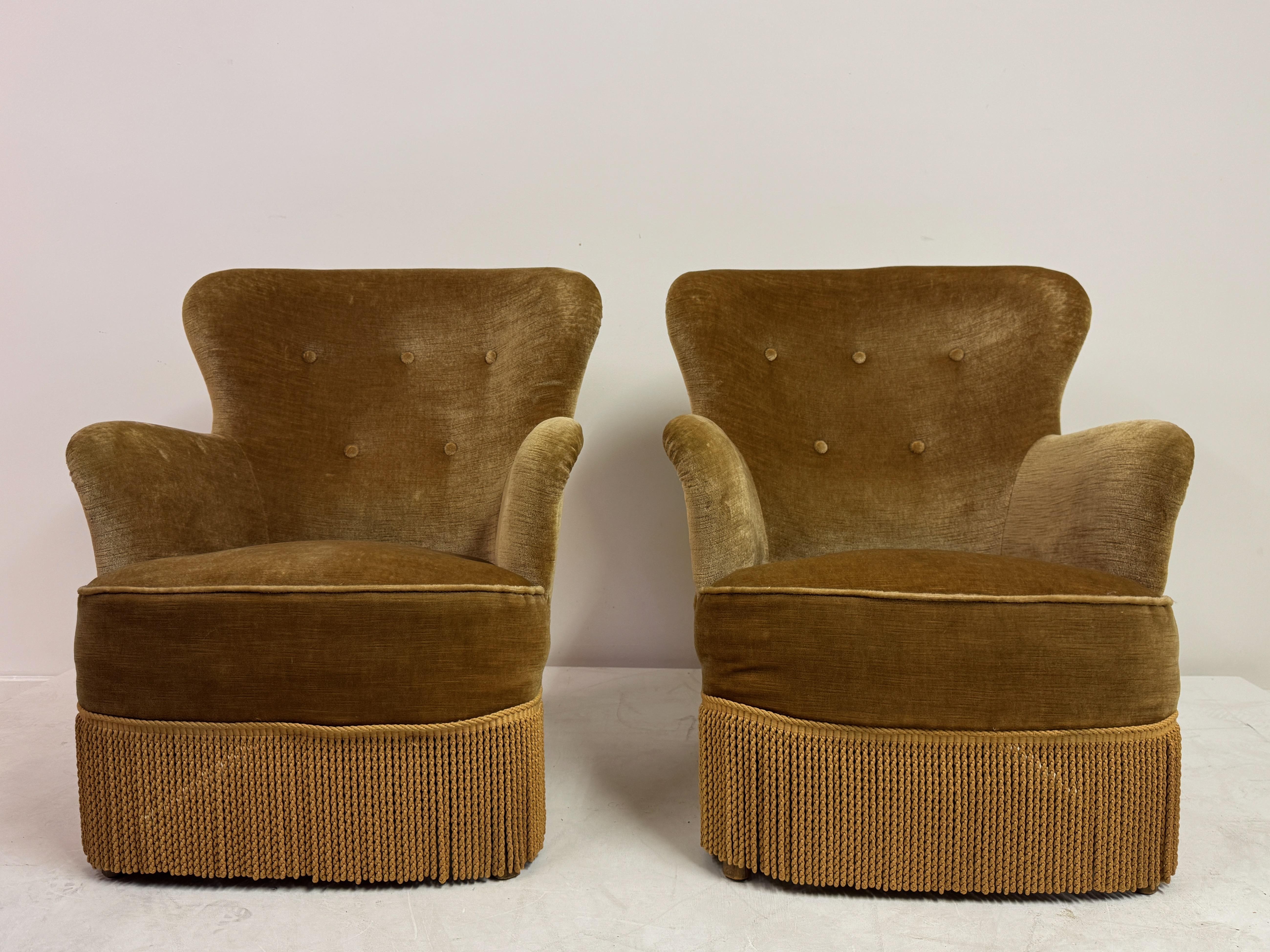 Pair of Danish Armchairs with Fringe Skirts, 1950s–1960s


A characterful pair of Danish armchairs dating from the 1950s–1960s, upholstered in a warm golden velvet with fringed skirts. Their generous, sculptural form reflects the playful yet