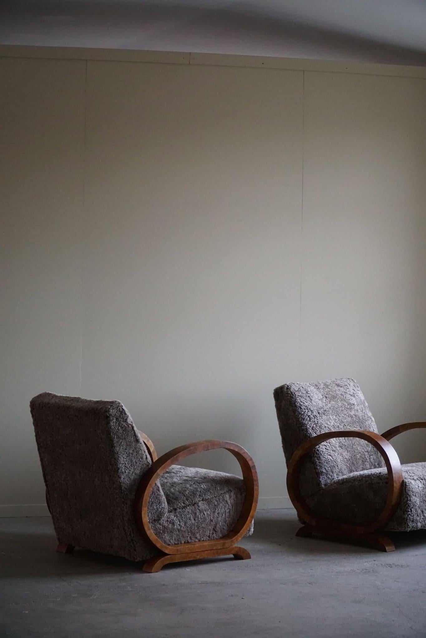 A beautiful pair of curved Art Deco lounge chairs, with armrest in walnut, made in the 1930s by a Danish cabinetmaker. Beautiful wood grains that complement these glamorous chairs. Reupholstered in great quality shearling lambswool.

This fine pair