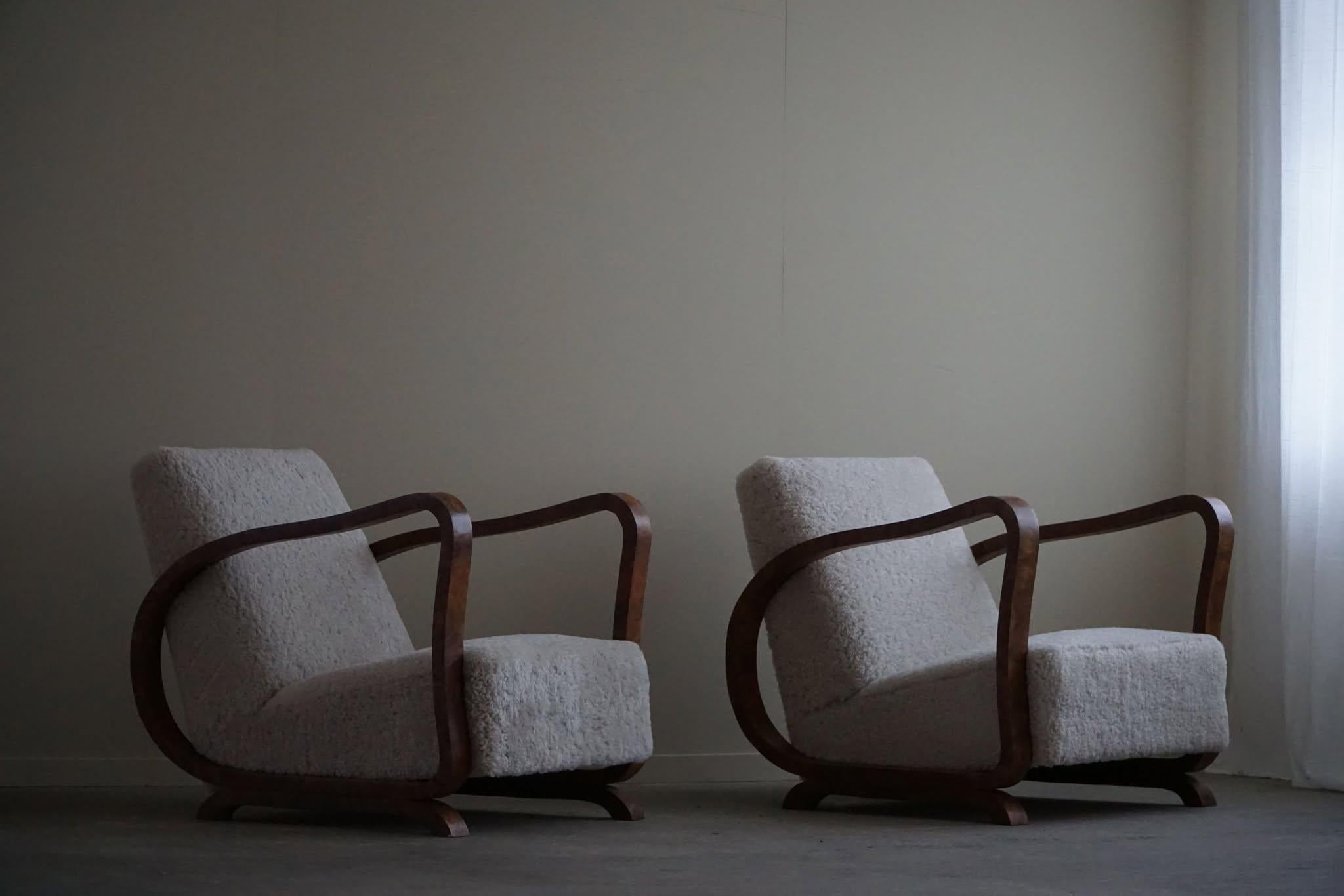 A beautiful pair of curved Art Deco lounge chairs, with armrest in walnut, made in the 1930s by a Danish cabinetmaker. Beautiful wood grains that complement these glamorous chairs. Reupholstered in great quality shearling lambswool.

This fine pair