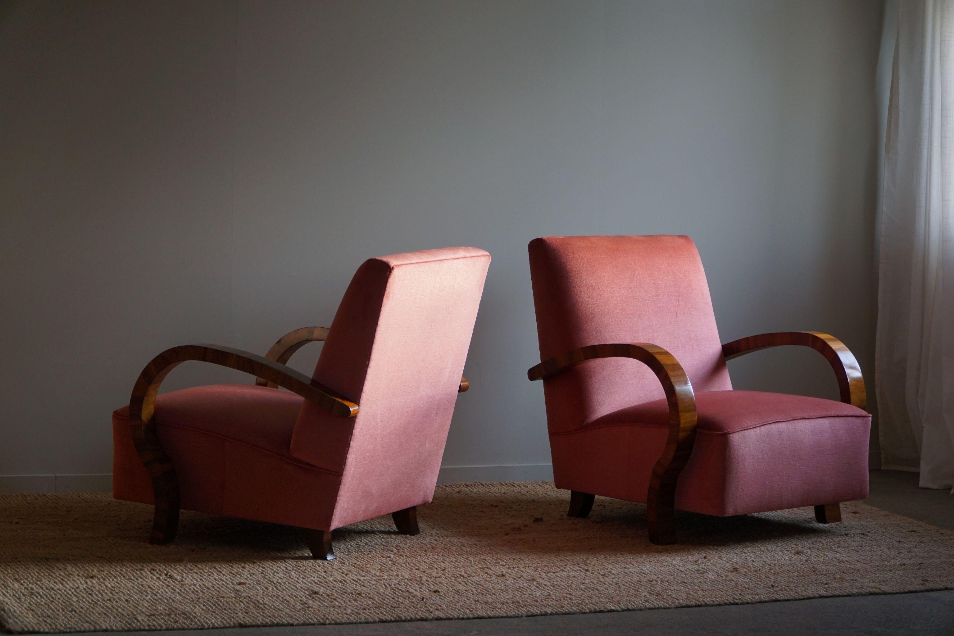Such a beautiful and decadent pair of curved Art Deco lounge chairs, with armrest in walnut, made in the 1930s by a Danish cabinetmaker. Beautiful wood grains that complement these glamorous chairs. Reupholstered in great quality pink velvet.

This