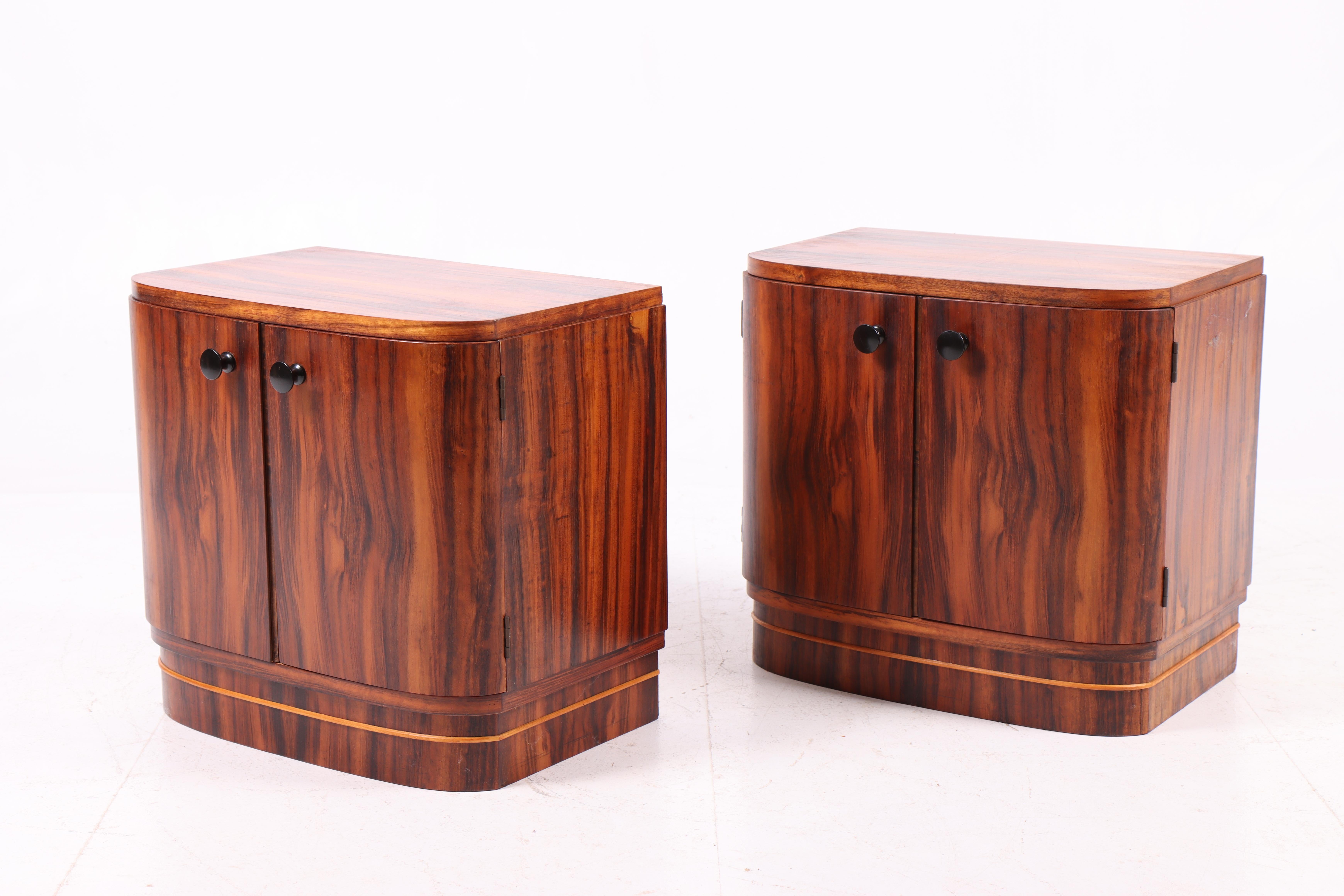 Beautiful pair of nightstands crafted by a Danish cabinetmaker in the 1950s. Made of walnut with a vivid grain pattern and softly rounded form, the design clearly reflects the Art Deco influence of the period. Each cabinet features double doors with