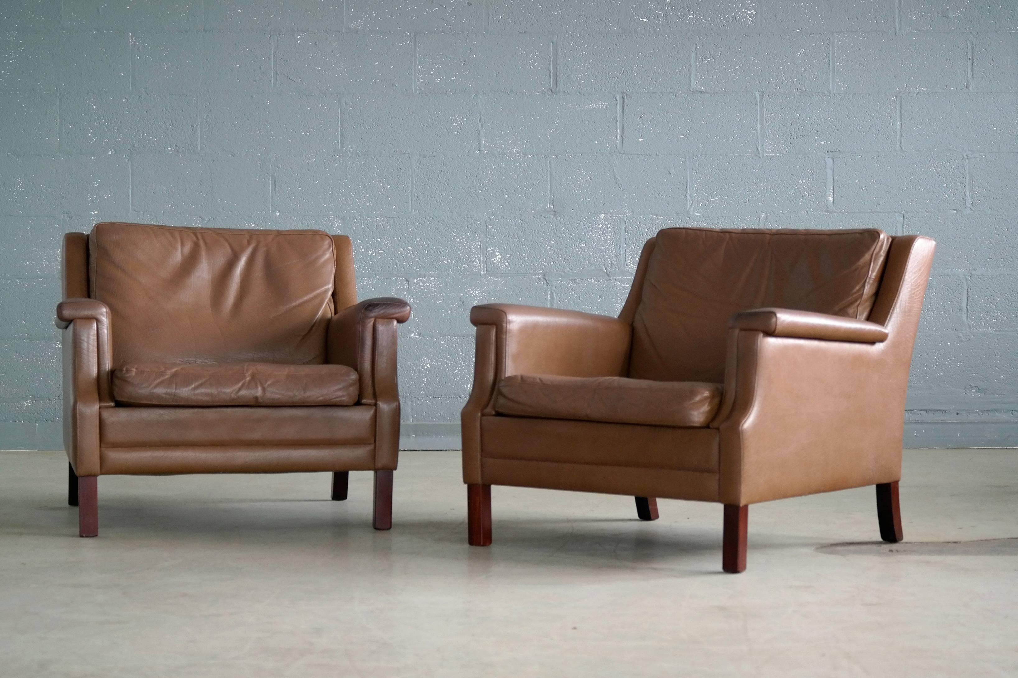 Elegant pair of Danish midcentury easy lounge or club chairs in the style of Borge Mogensen. These chairs have a slightly more intricate and formal armrest design giving them a nice presence. The leather shows natural wear and patina throughout and