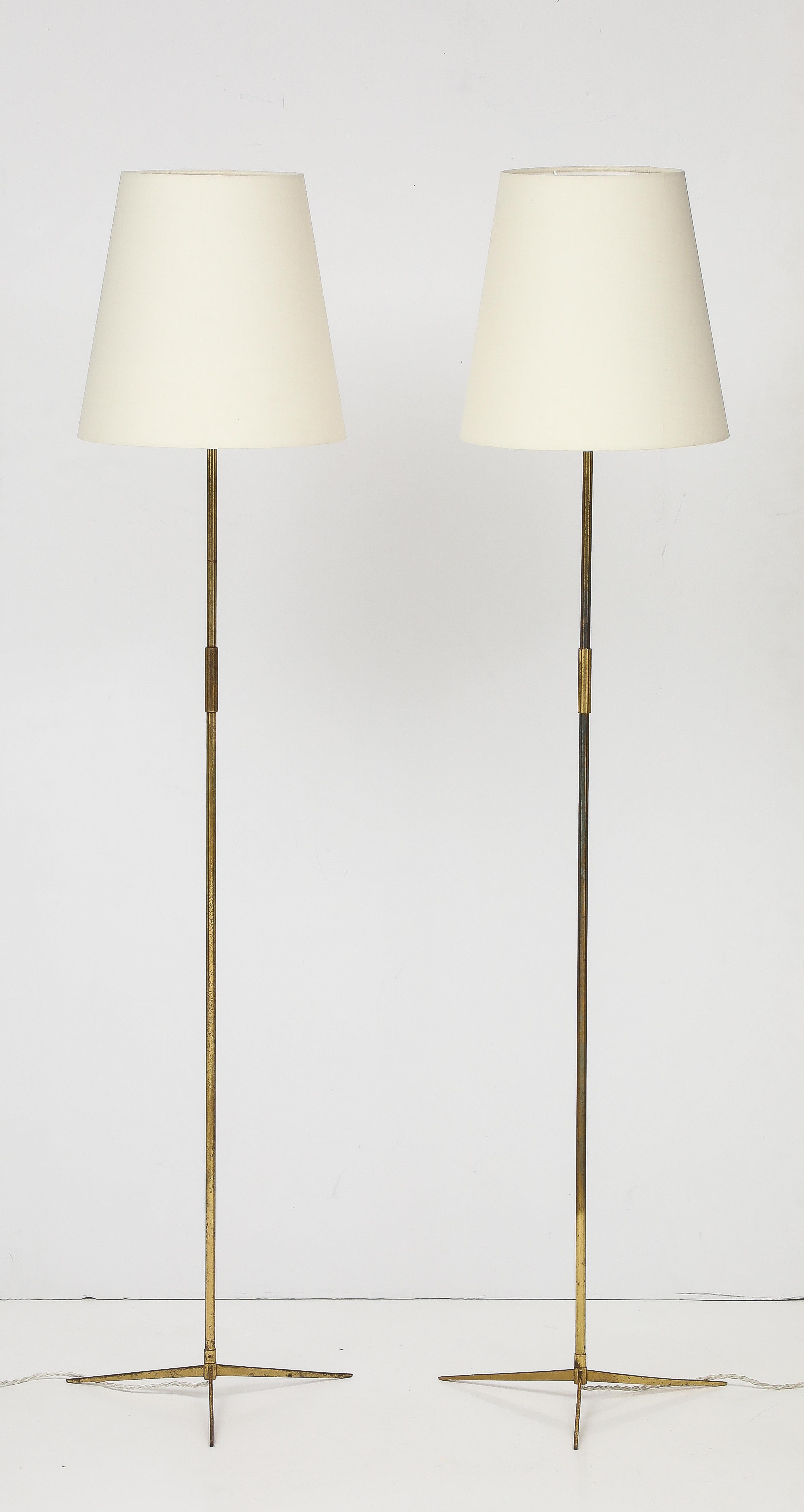 Paire de lampadaires danois en laiton avec abat-jour. Lampes à pied tripodes en laiton à l'esthétique sophistiquée et minimaliste. Le laiton est patiné par l'âge et les teintes sont assorties, prêtes à être installées et appréciées.