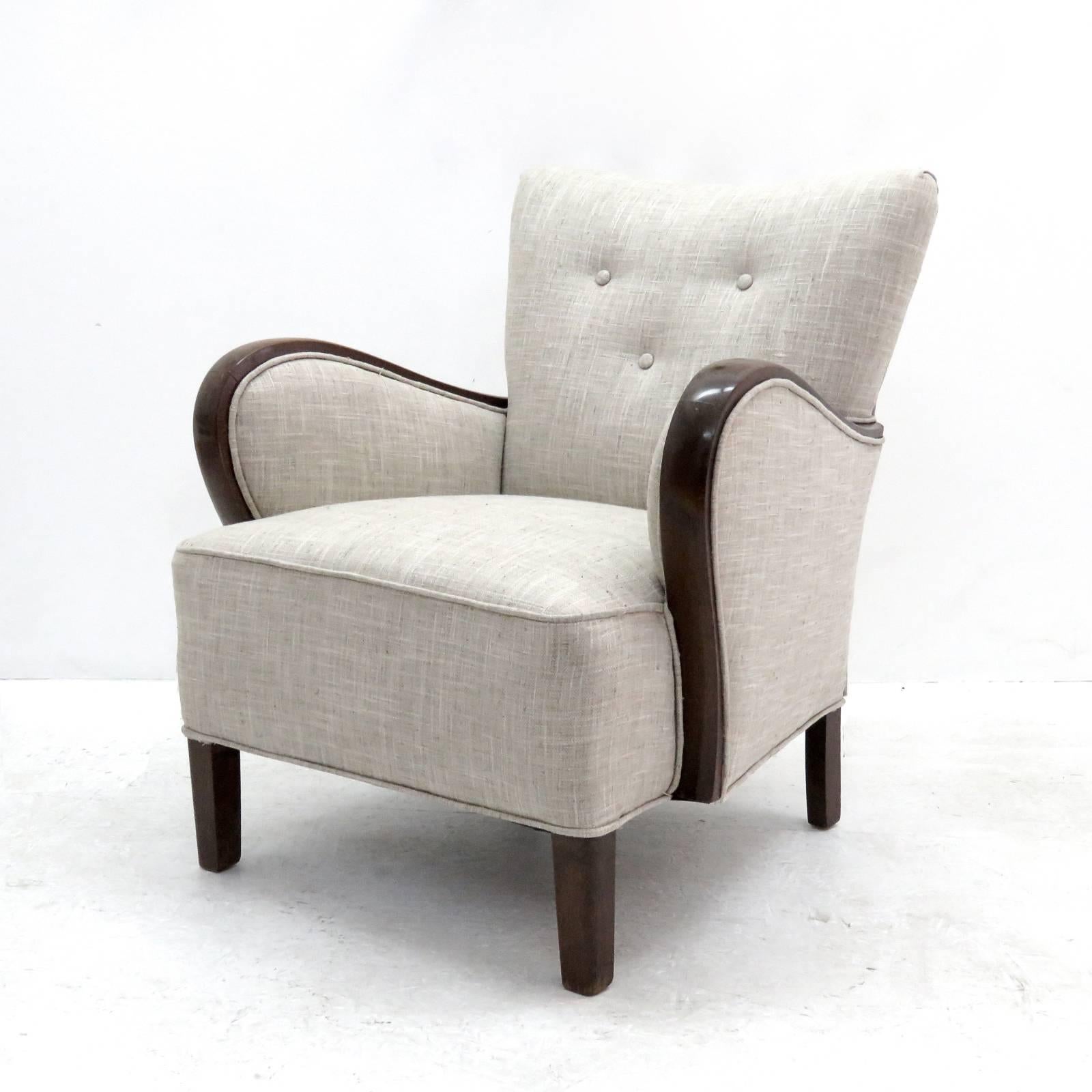 Striking 1940s pair of Danish armchairs with curved armrests and tapered legs in darkened lacquered beech, newly upholstered.