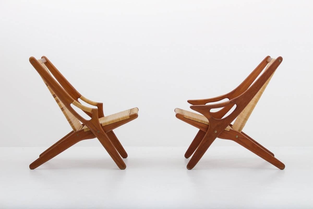 Superbes fauteuils d'Arne Hovmand-Olsen:: modèle 300:: en teck et en rotin. 
Le cadre de la chaise est souligné par deux pièces de bois de forme sculpturale:: qui se croisent sur les côtés de la chaise. Les poignées sont joliment intégrées au
