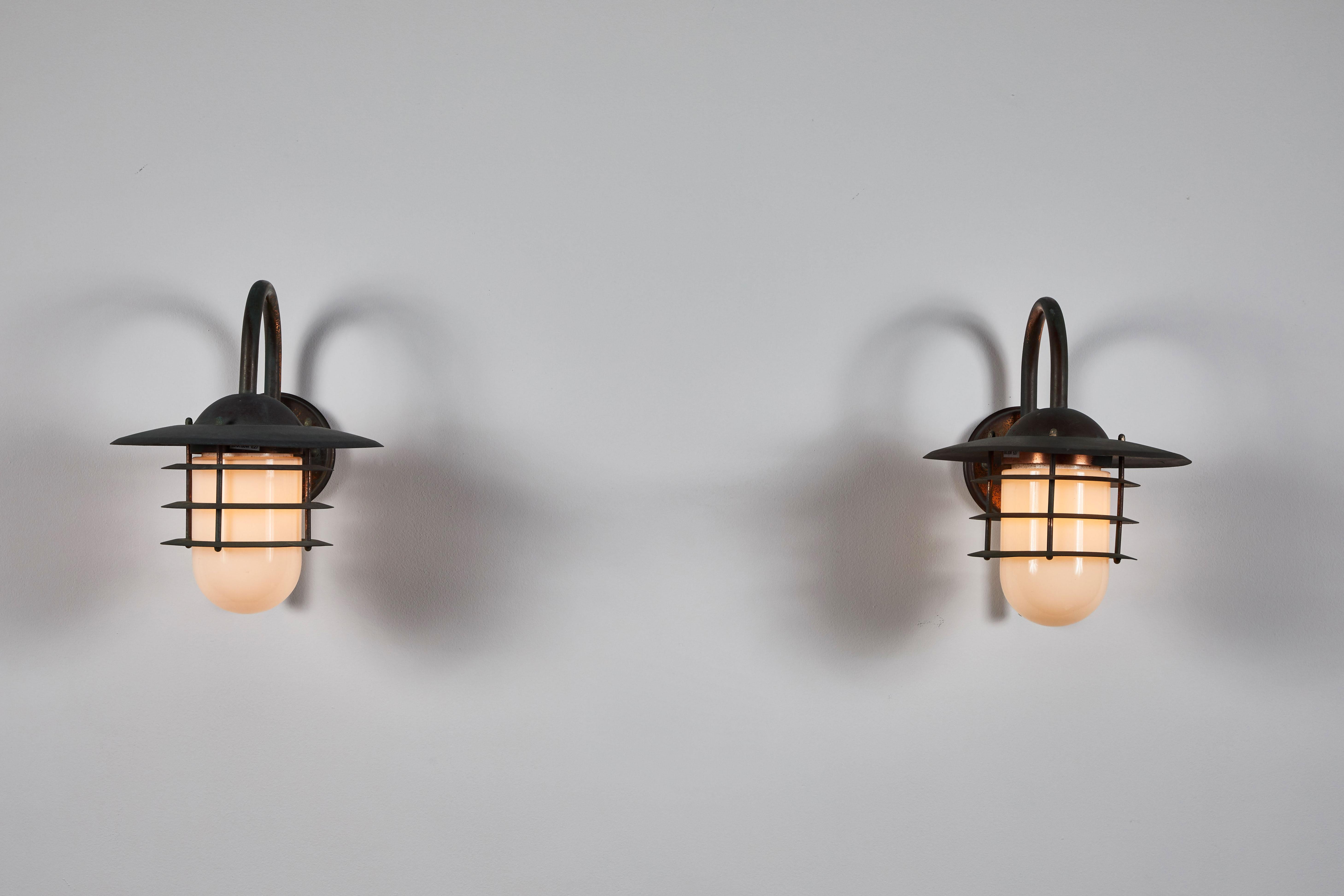 Pair of exterior sconces manufactured in Denmark, circa 1960s. Patinated copper with opaline glass. Rewired for US junction boxes. Each sconce takes one E27 60w maximum bulb. Bulbs provided as a one time courtesy.
