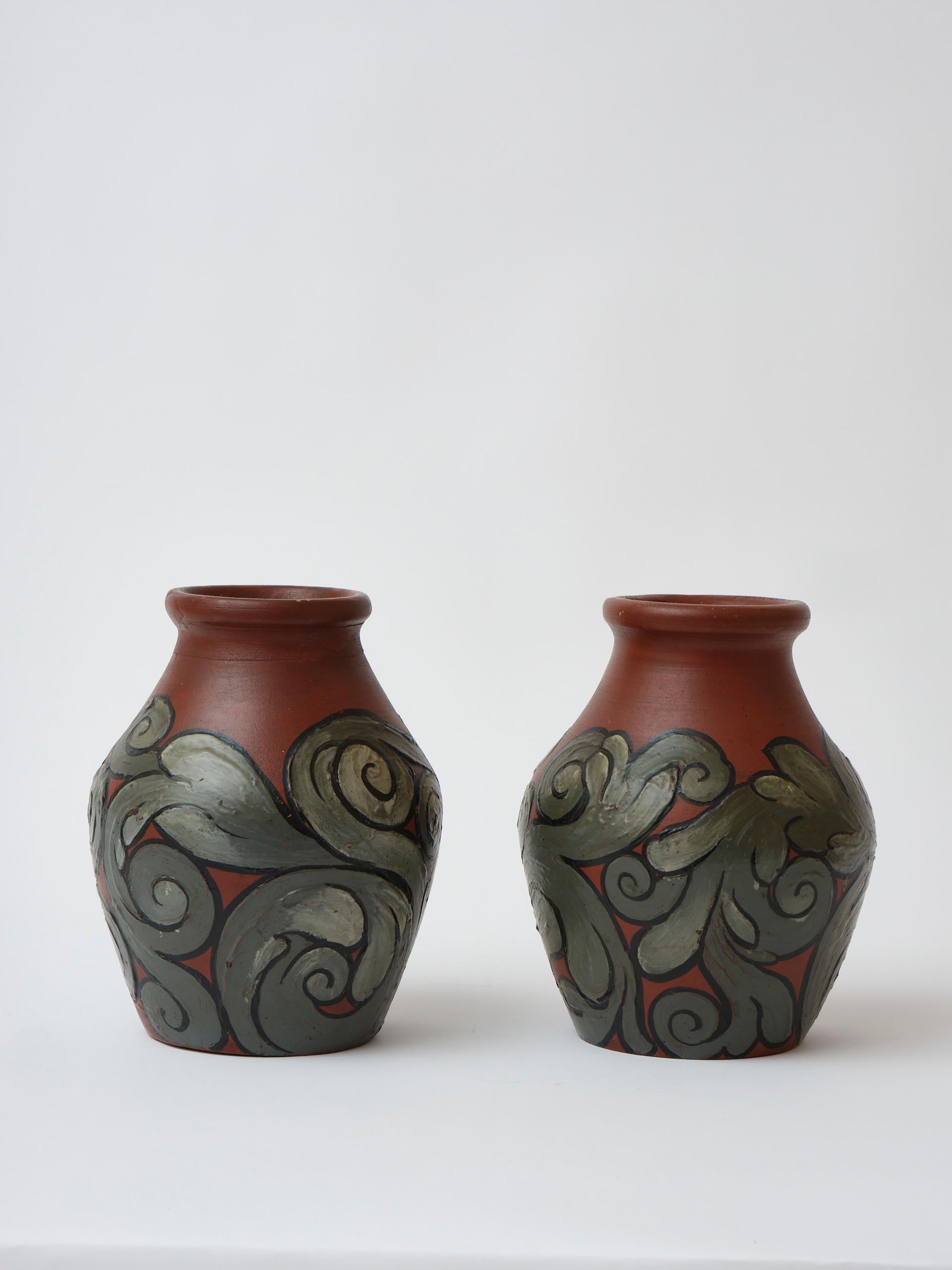 Amazing and unique pair of Danish hand made earthenware vases in Art Nouveau style with ‘Skønvirke’ (Arts & Crafts) decorations in earthy tones. 
When examining the vases close up you will see that, though shaped and decorated the same way, they are