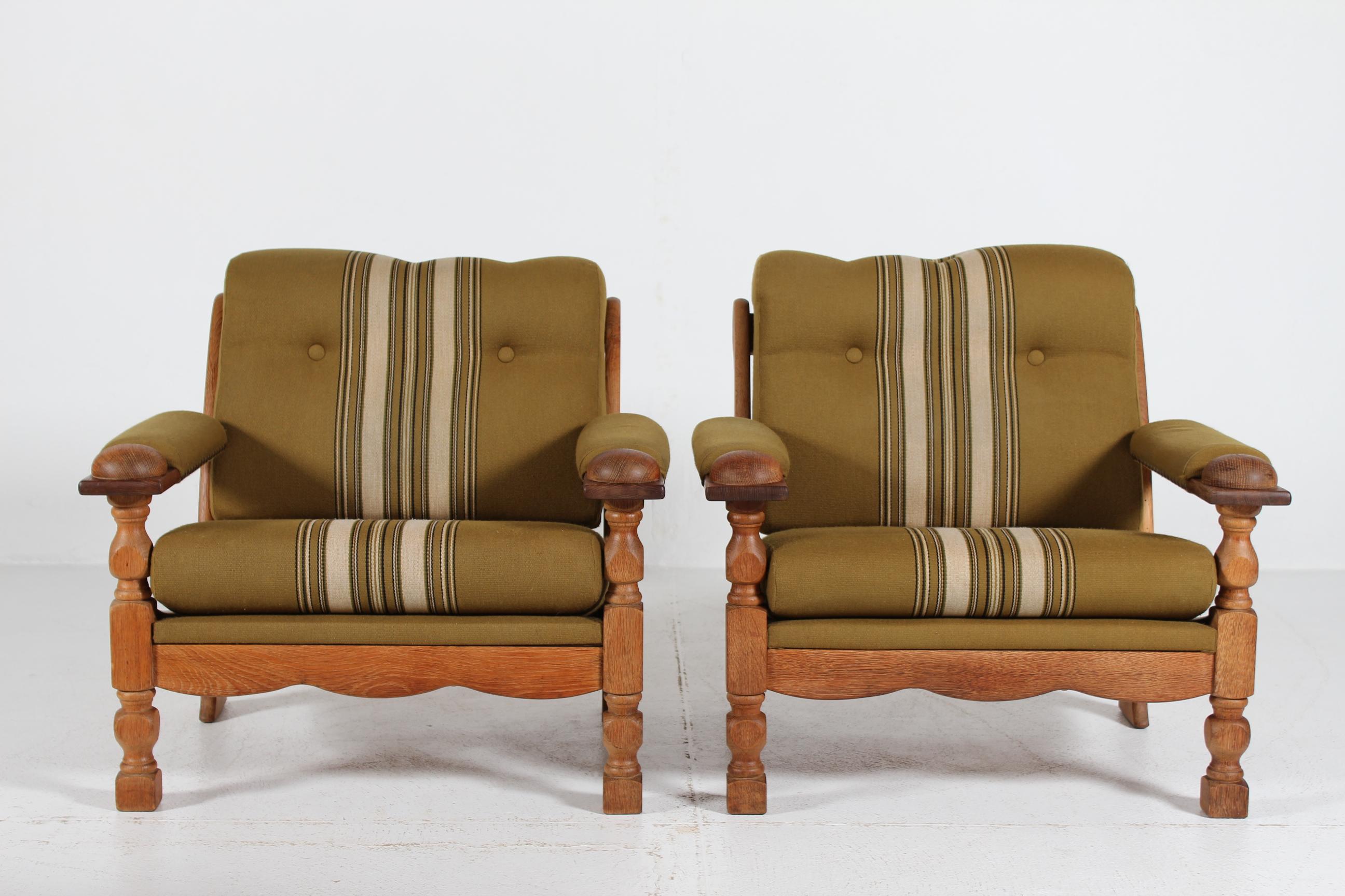 A stunning pair of vintage Danish Henning Kjærnulf lounge chairs.
They are most likely manufactured in Denmark by EG Møbler.

The set has frames and armrests of turned and carved solid oak upholstered with the original used striped woolen fabric