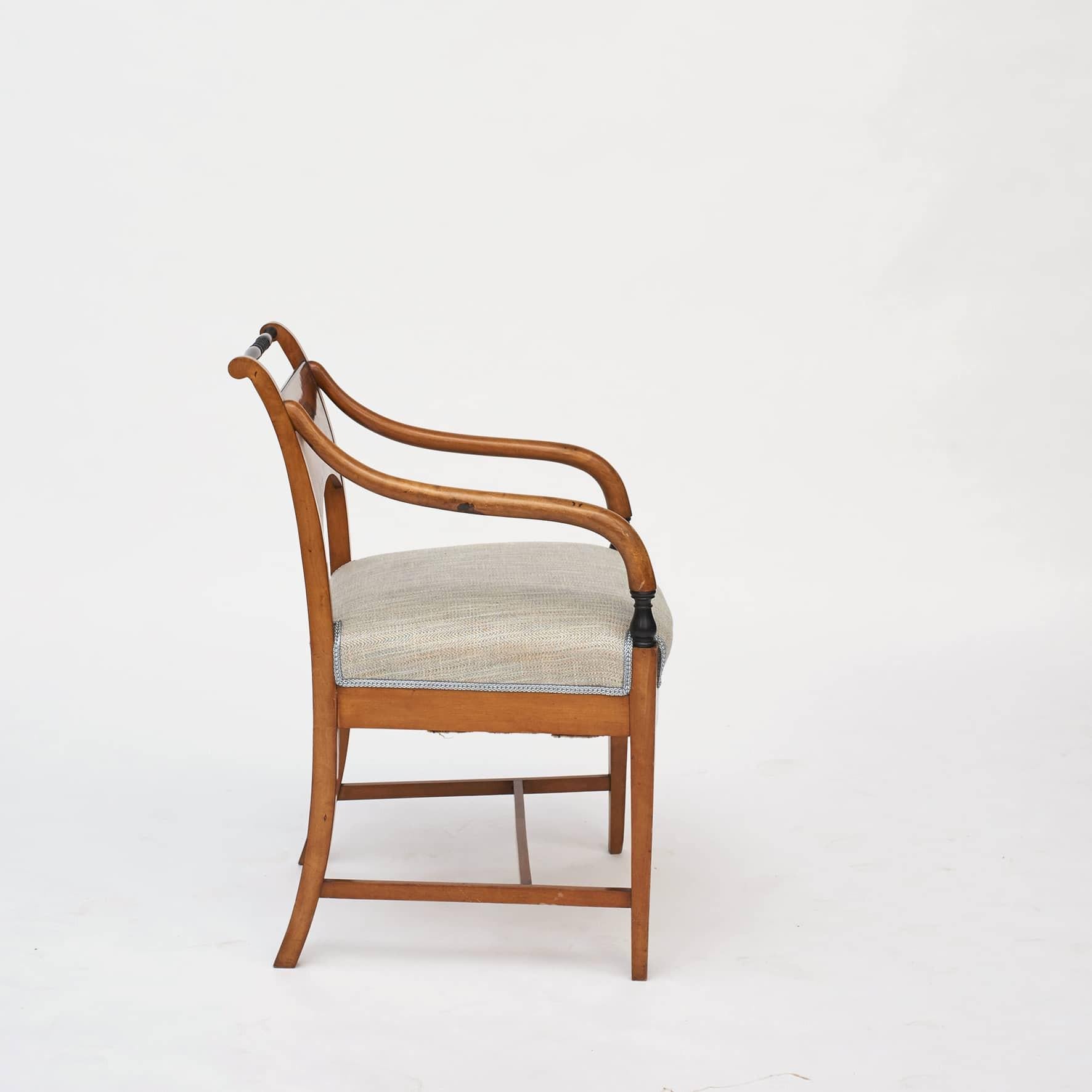 Una coppia di eleganti poltrone tardo impero.

Realizzata in legno di betulla con intarsi sullo schienale a forma di vasi. Intarsi a linee sottili su schienale e grembiule.
La parte superiore delle guide delle sedie dello schienale è in legno