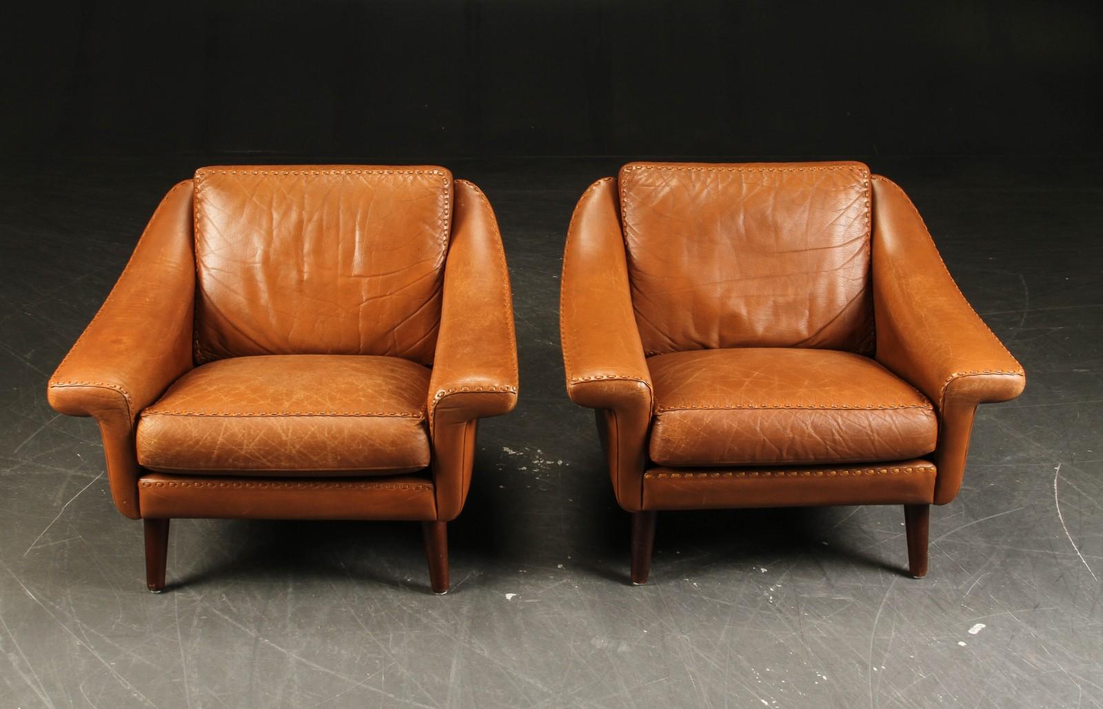 Very comfortable pair of lounge chairs, Danish Modern, in caramel-colored leather, good condition. The classic chairs for library or living room, from 1960's.