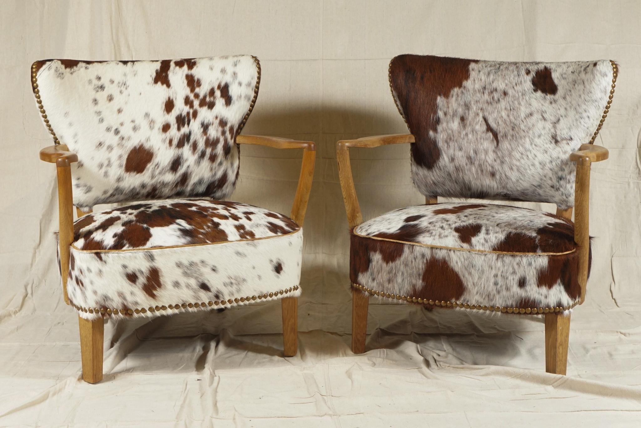 Delightful pair of Danish modern cabinet-maker armchairs, by S. Thrane & Søn, Odense, with stylishly curved open arms and slightly curved back, in light-colored oak, freshly upholstered in a multi-patterned, soft brown and white cowhide.
