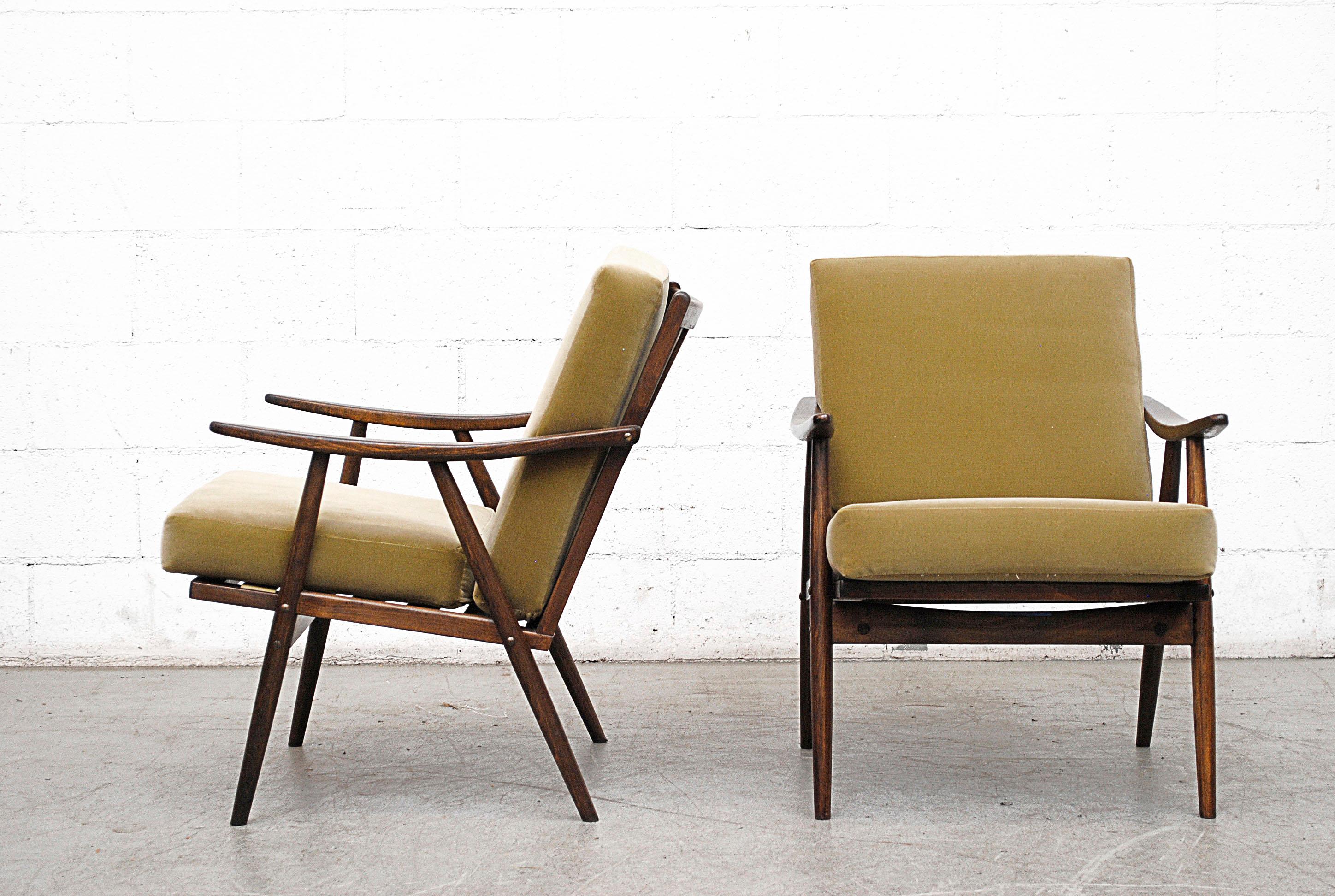 Set of two matching midcentury lounge chairs, newly upholstered in leaf green velvet. Lightly refinished dark wood frames with organically carved armrests.