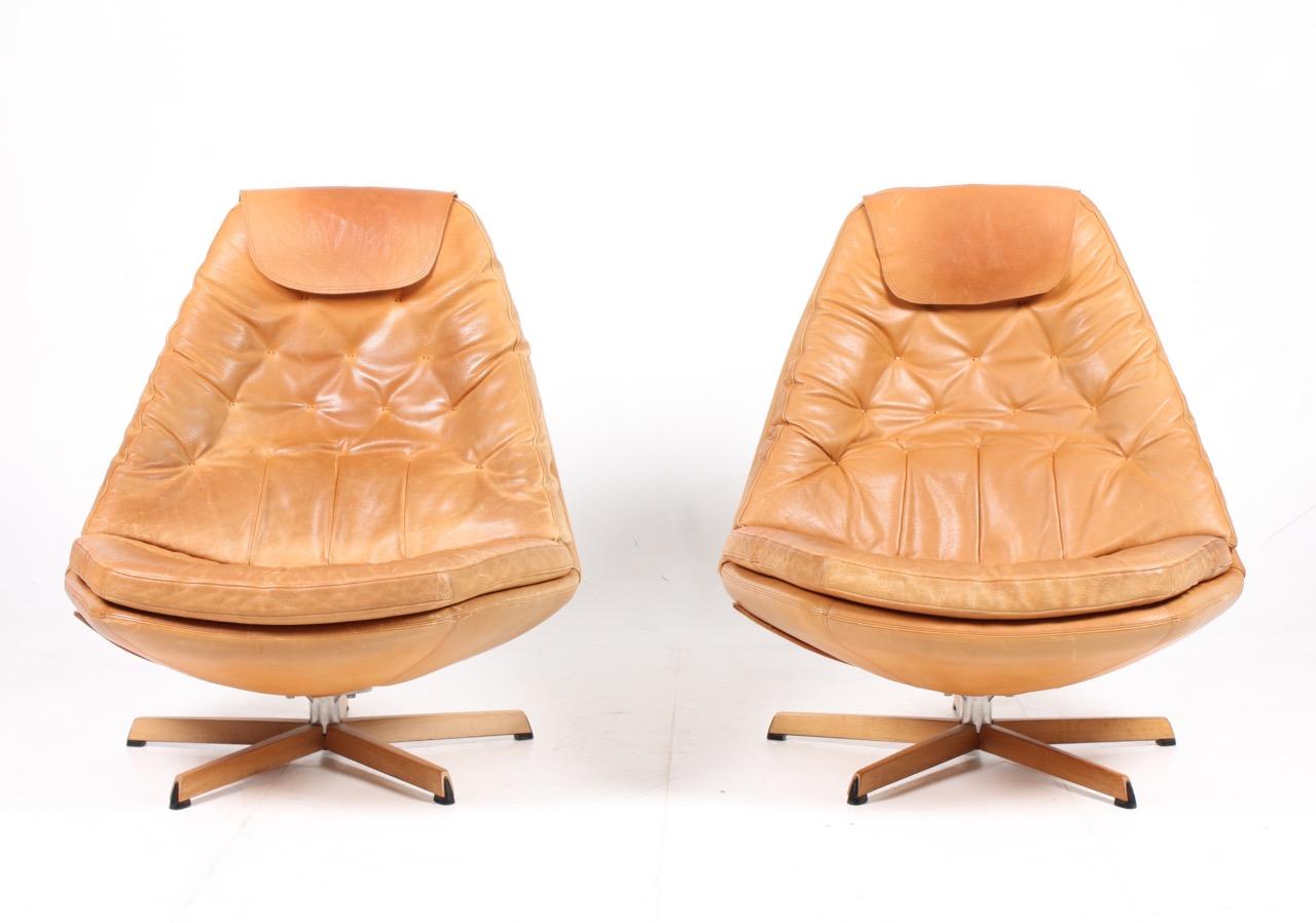 Pair of great looking and very comfortable swivel chairs with matching foot stools in beautifully patinated leather, designed by Danish architects Madsen & Schubell in the 1970s. Great original condition.