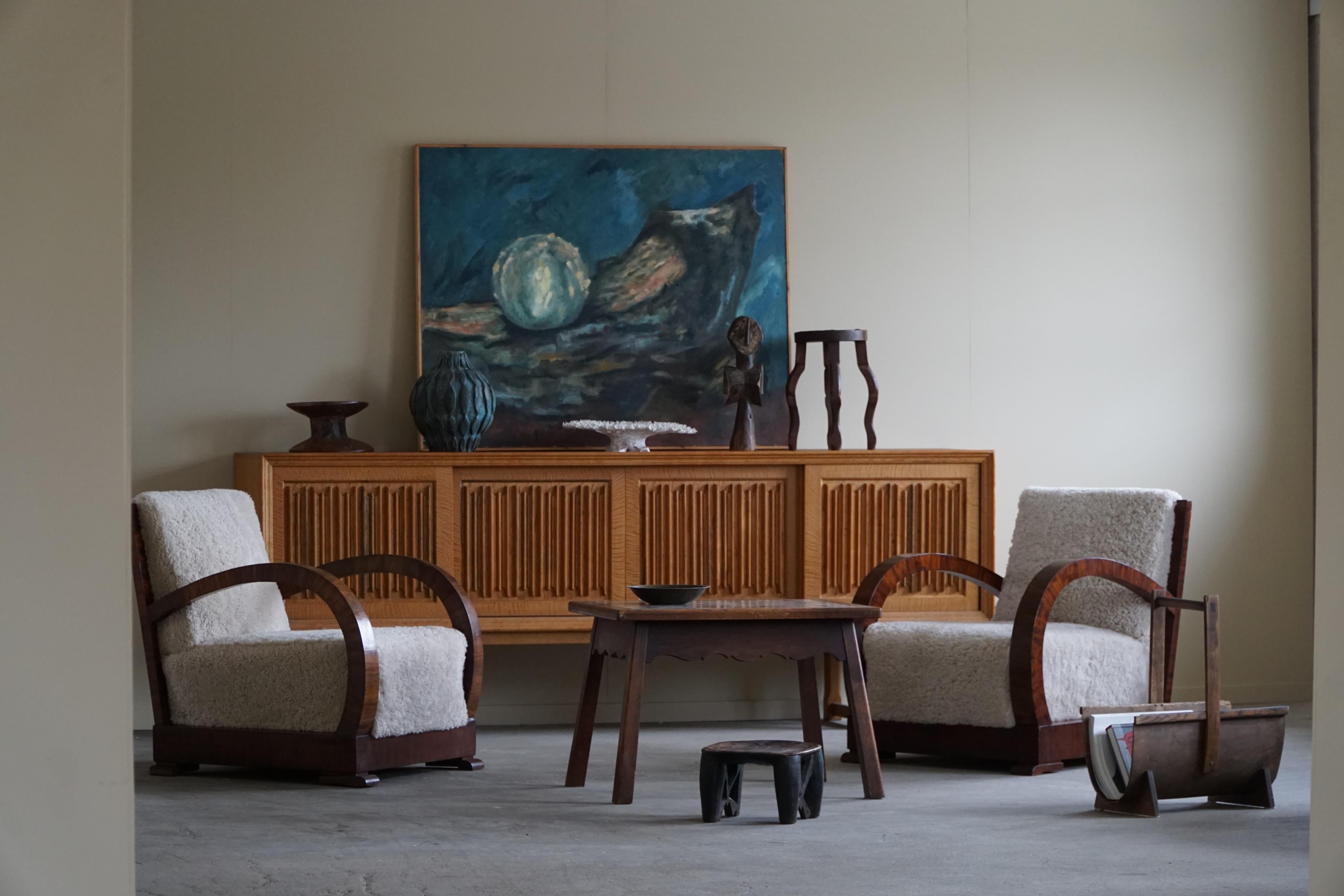 Pair of curved Art Deco lounge chairs, with armrest in walnut, made in 1930s by a Danish cabinetmaker. The chairs have been recently reupholstered in luxurious lambswool from SIPO, adding a touch of warmth and texture to the design. The lambswool is