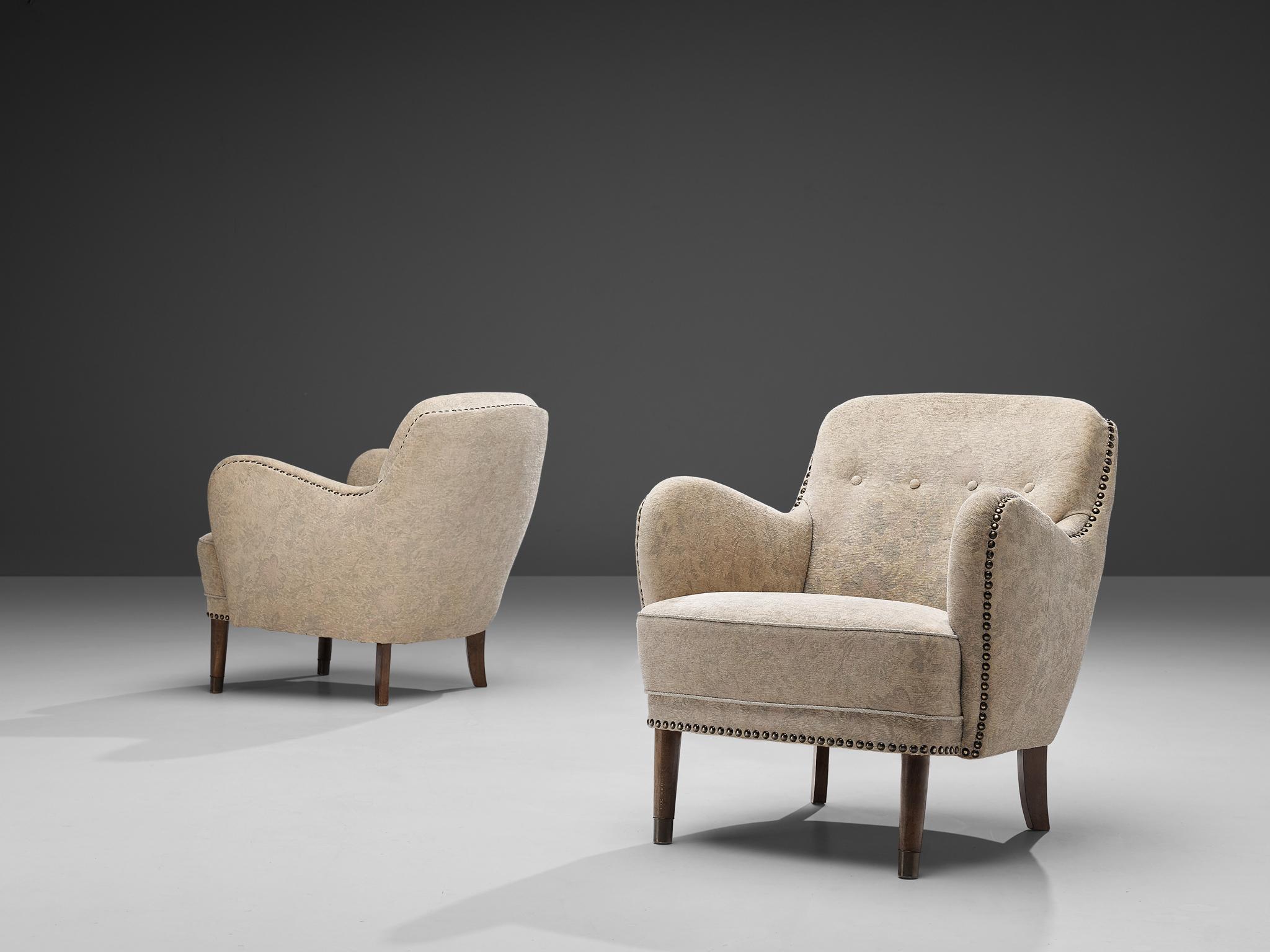 Art Deco lounge chairs, stained beech, fabric, brass nails, Denmark, 1940s

This pair of easy chairs features dynamic formed armrests pointing upwards. The backrest is slightly tilted backwards and decorated with tufted details. Beautiful lines of