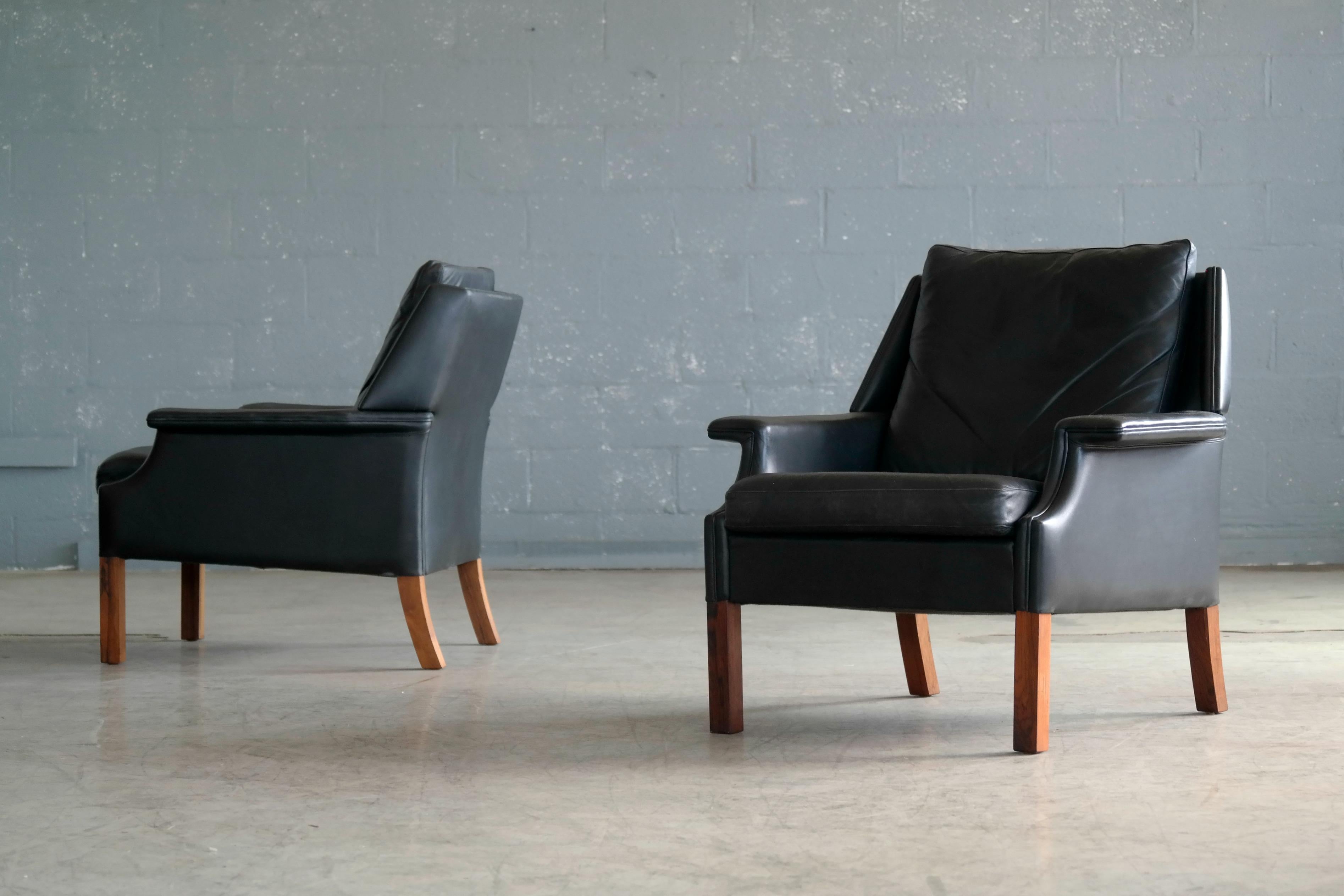 Superb pair of Danish Georg Thams designed 1960s lounge chair in black leather with rosewood legs. Very high end build quality and great design details. Rich in details with nice natural wear and patina to the leather which remains supple and in