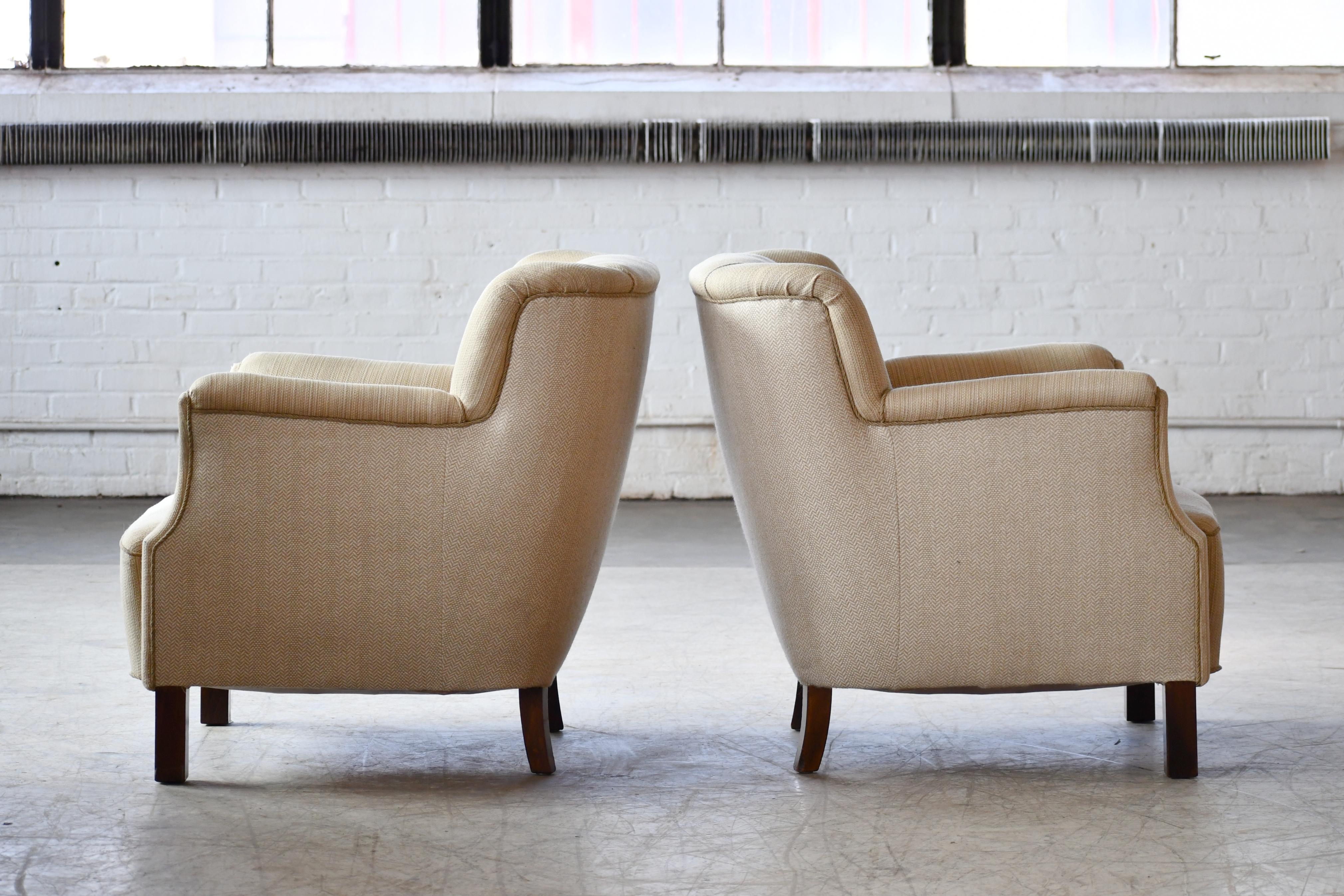 Classic Danish lounge chairs ca. 1940's and very much in the style and tradition of Fritz Hansen. The front legs are very much in the design and spirit of Fritz Hansen. Hansen liked square simple legs like seen on this pair. Coil springs in seat and