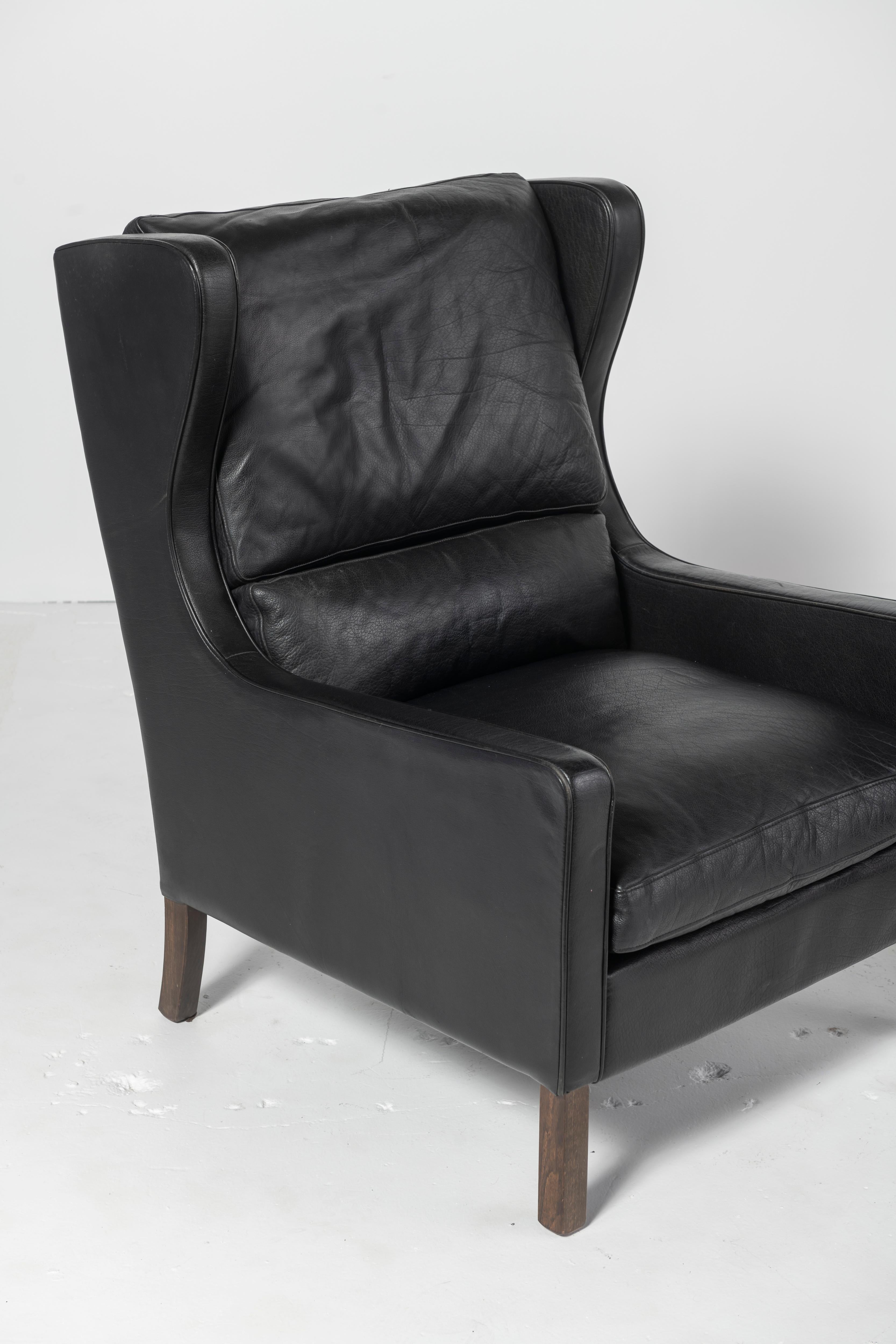 Two Mid-Century Danish Modern wingback leather chairs in black attributed to Børge Mogensen. Original leather on both chairs which are not only comfortable but have a beautifully lustrous patina.