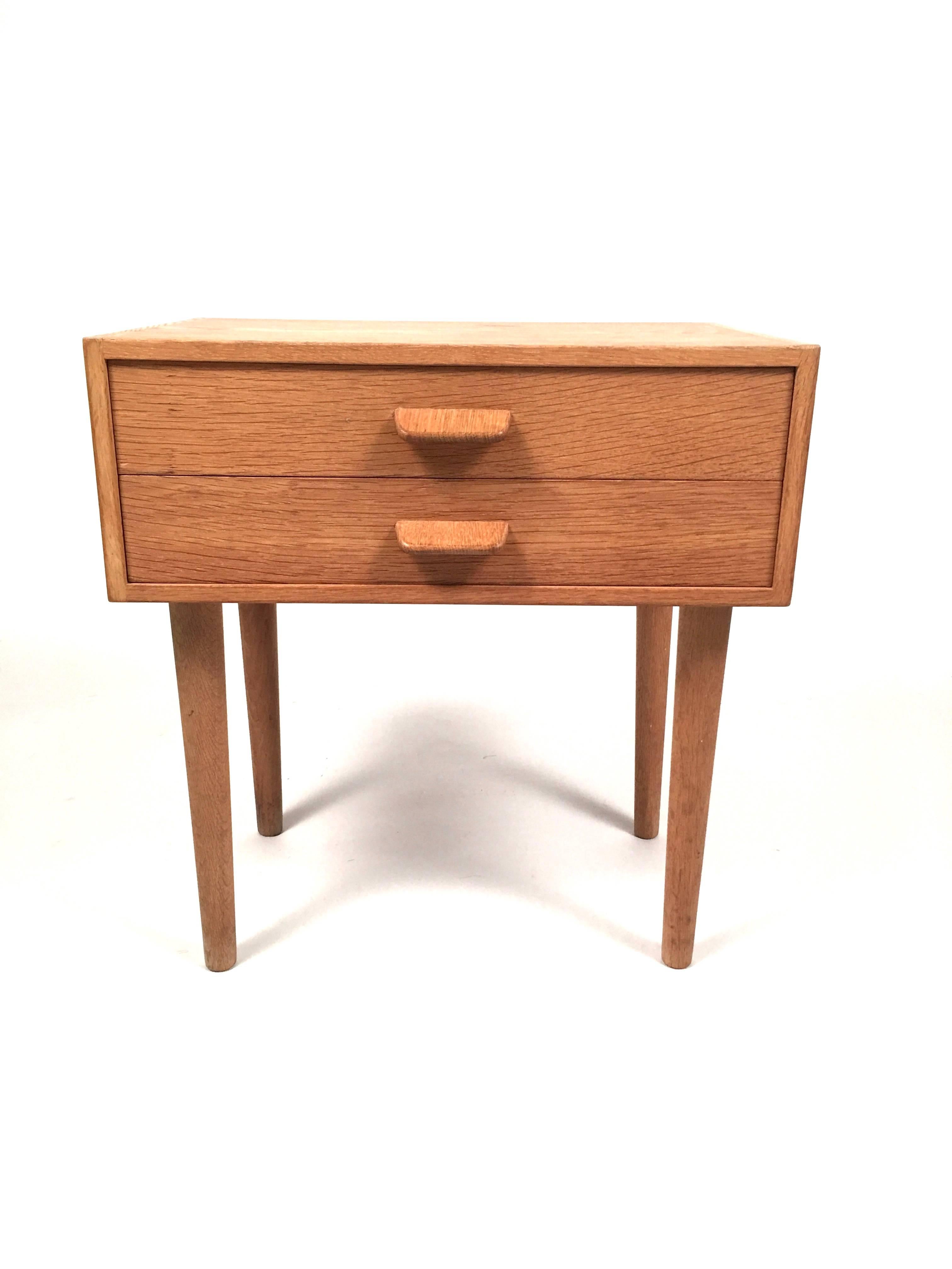 A pair of Mid-Century Modern end tables in oak designed by Danish furniture designer, Poul M. Volter, of rectangular form, with two drawers, each with wonderfully simple and functional oak tab pulls, raised on four cylindrical tapering legs,