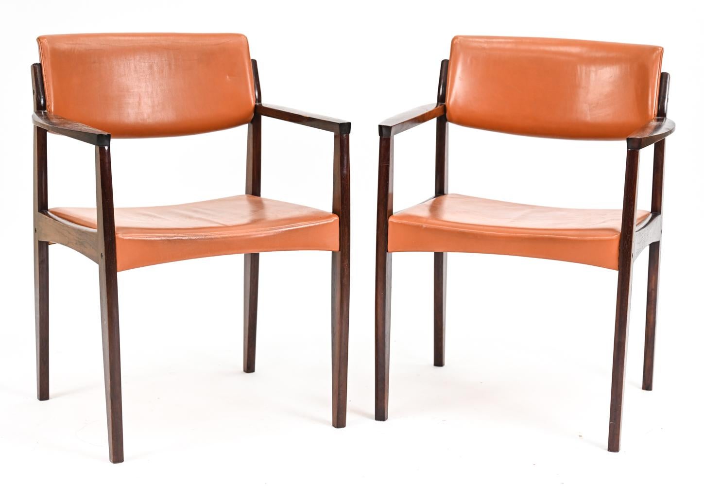 An attractive pair of Danish mid-century armchairs in orange leather with modern angular frames in handsome rosewood. A stylish pair for use at either end of a dining table or accent pieces in a living space. 
No manufacturer's labels present.