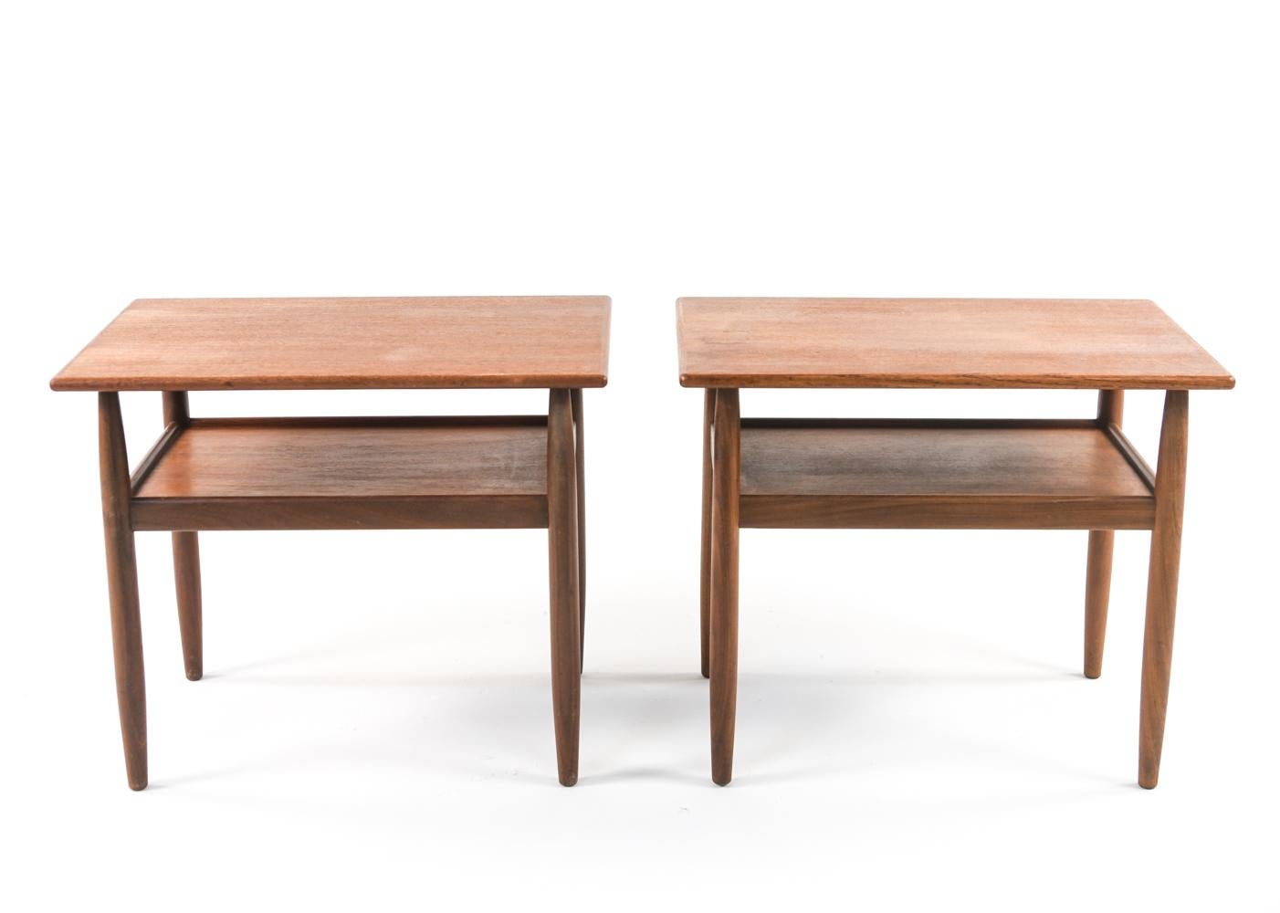 A pair of charming Danish mid-century two-tier side tables in teak wood designed by Ejvind A. Johansson for Vitre, c. 1960's. Retaining Vitre label underneath.