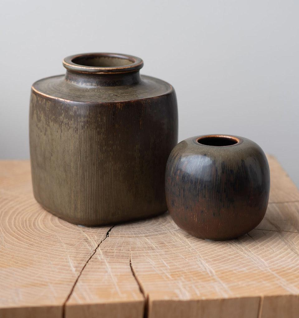 A pair of Danish midcentury ceramic vessels with lightly striated surface and haresfur glazing in rich oak, coffee, and olive-toned hues. Design by Valdemar Peterson for Bing & Grøndahl, with hallmark on bottom. Sold as a set.

Denmark, circa