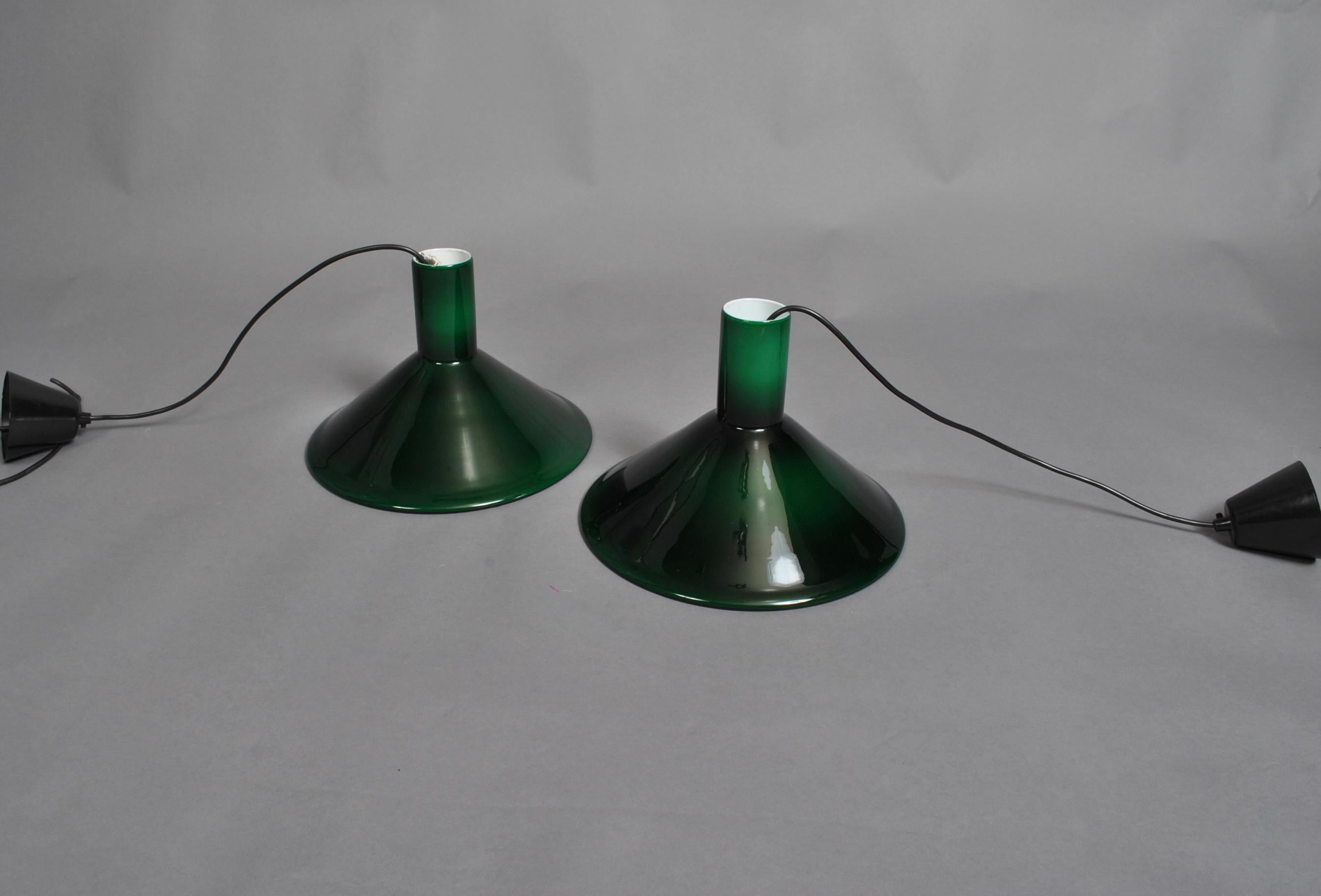 A pair of P&T pendant lights designed by Michael Bang for Holmegaard, 1972. Perfect midcentury accents. 
Green Holmegaard glass with white inner casing. Cable can be height adjusted.