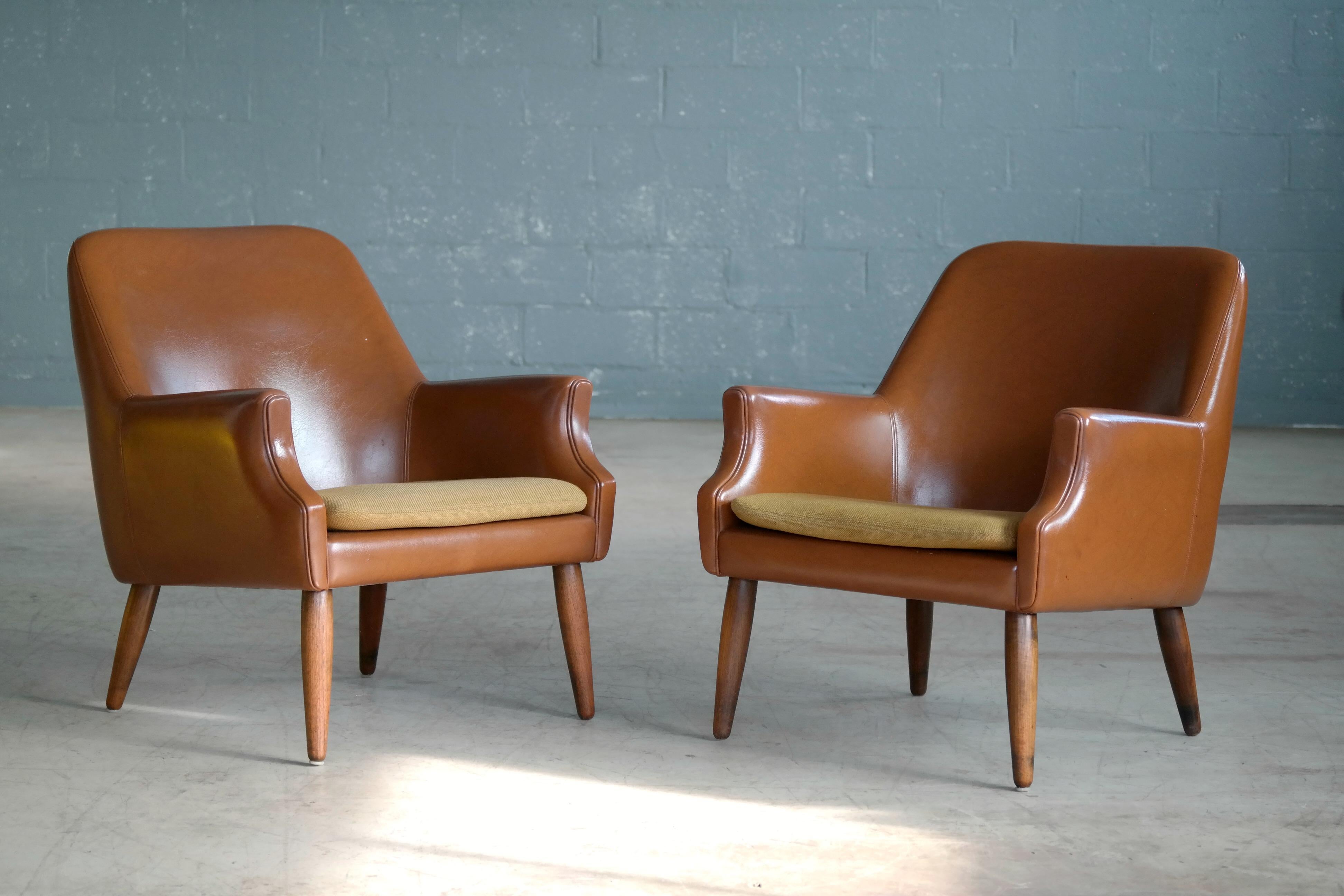 Very cool pair of Danish, 1960s lounge chairs covered in vinyl or Naugahyde raised on solid teak legs and made in Denmark in an era when 100% vinyl was the real thing. Very good condition with great patina to the vinyl i.e small areas where the
