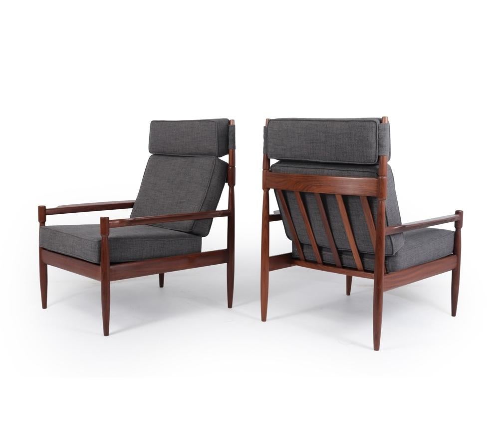 A pair of Danish produced armchairs made in solid Afromosia with good strong construction and very unusual and stylish horned uprights to hold the head cushion. The frames have been fully polished, the webbing has been replaced and the cushions are