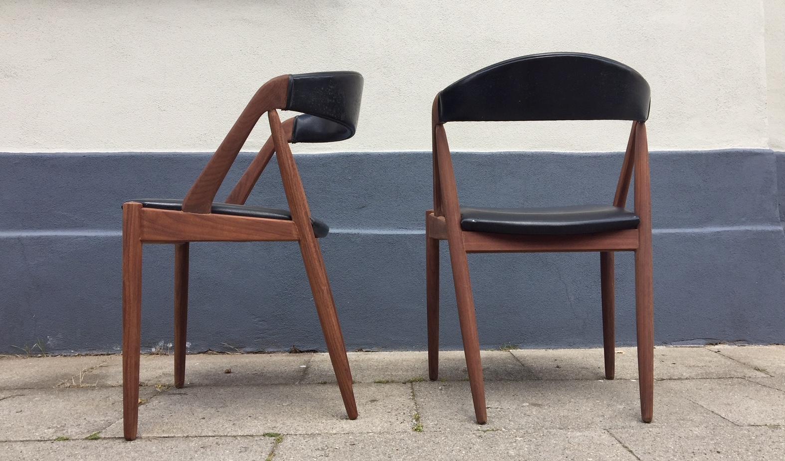 A pair of Kai Kristiansen model 31A dining chairs in teak. Manufactured by Schou Andersen in Denmark during the 1960s. Original faux black leather upholstery with some signs of age and use.