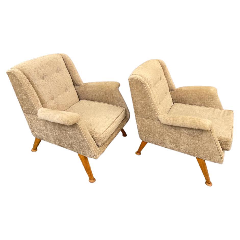 These upholstered armchairs crafted in the 1960 recalls the aesthetic of Danish functionalism. The armchairs feature a comfortable backrest and angular, slightly asymmetrical wooden legs on round feet.
The mellowly tint of the upholstery is