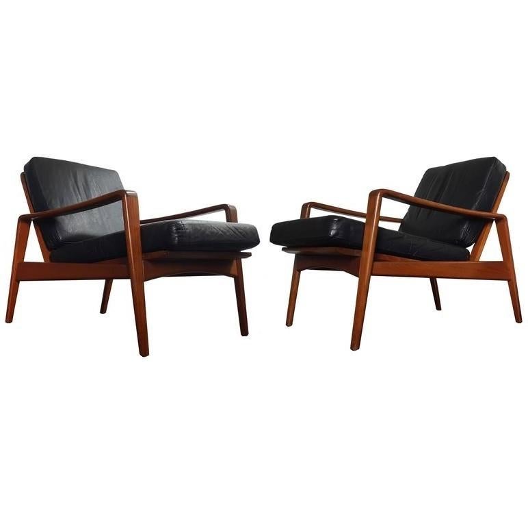Beautiful pair of easy chairs model no. 30 designed by Arne Wahl Iversen for the manufacturer Komfort. Made in Denmark. Featuring organic ribbon like Teak wood frames with black upholstered back and seat cushions.