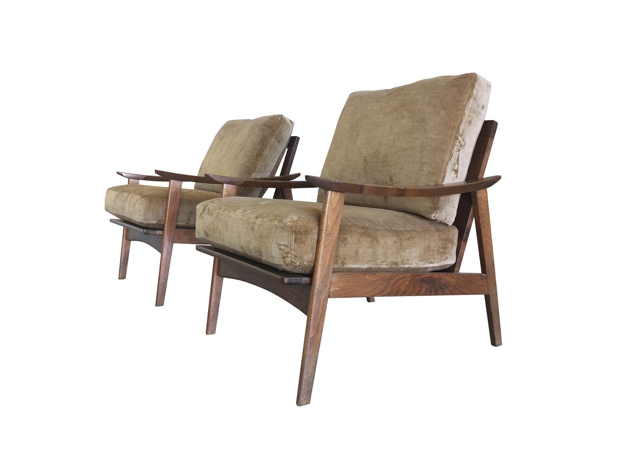 A pair of handsome lounge armchairs handmade in Denmark, mid-20th century. Their frames are maple wood crafted in a sleek, minimal design. Smooth, beautifully rounded edges characterize their modern style, as do the slanted legs that give the frame