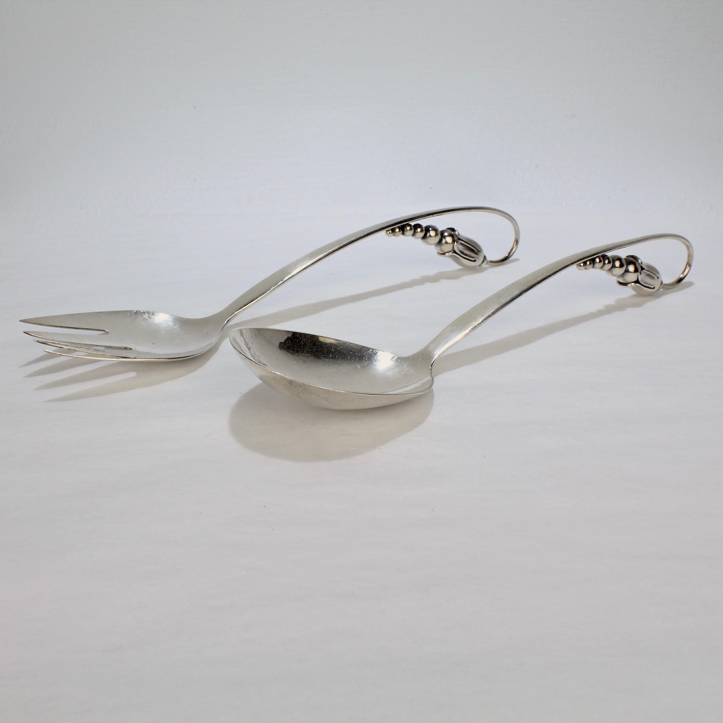 A superb pair of modernist sterling silver salad servers.

In the Blossom Pattern by the Danish silversmith Orla Vagn Mogensen.

Marked to the reverse: 35, O. Mogensen, Sterling, and Denmark.

Fork Length: ca. 10 1/4 in.
Spoon Length: ca. 10 1/2