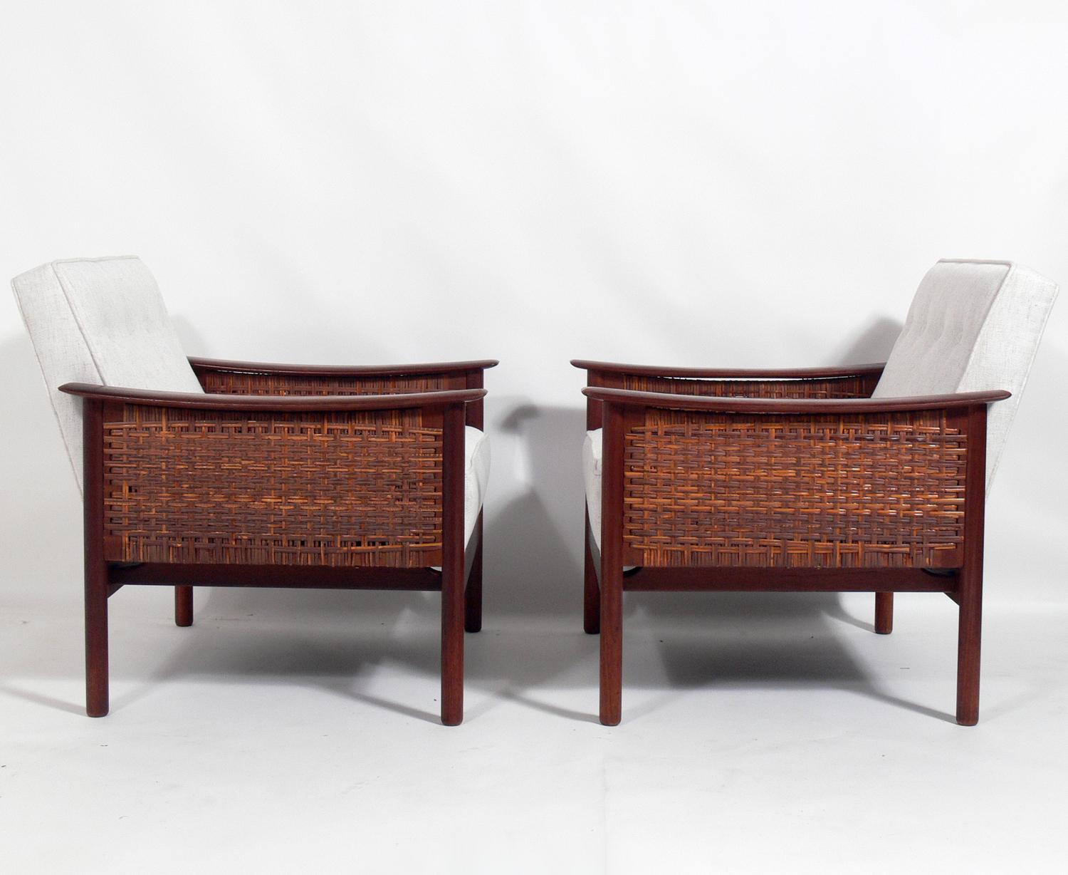 Pair of Danish modern caned lounge chairs, Denmark, circa 1960s. They have been recently reupholstered in an ivory color herringbone fabric. The teak frames have been cleaned and Danish oiled.