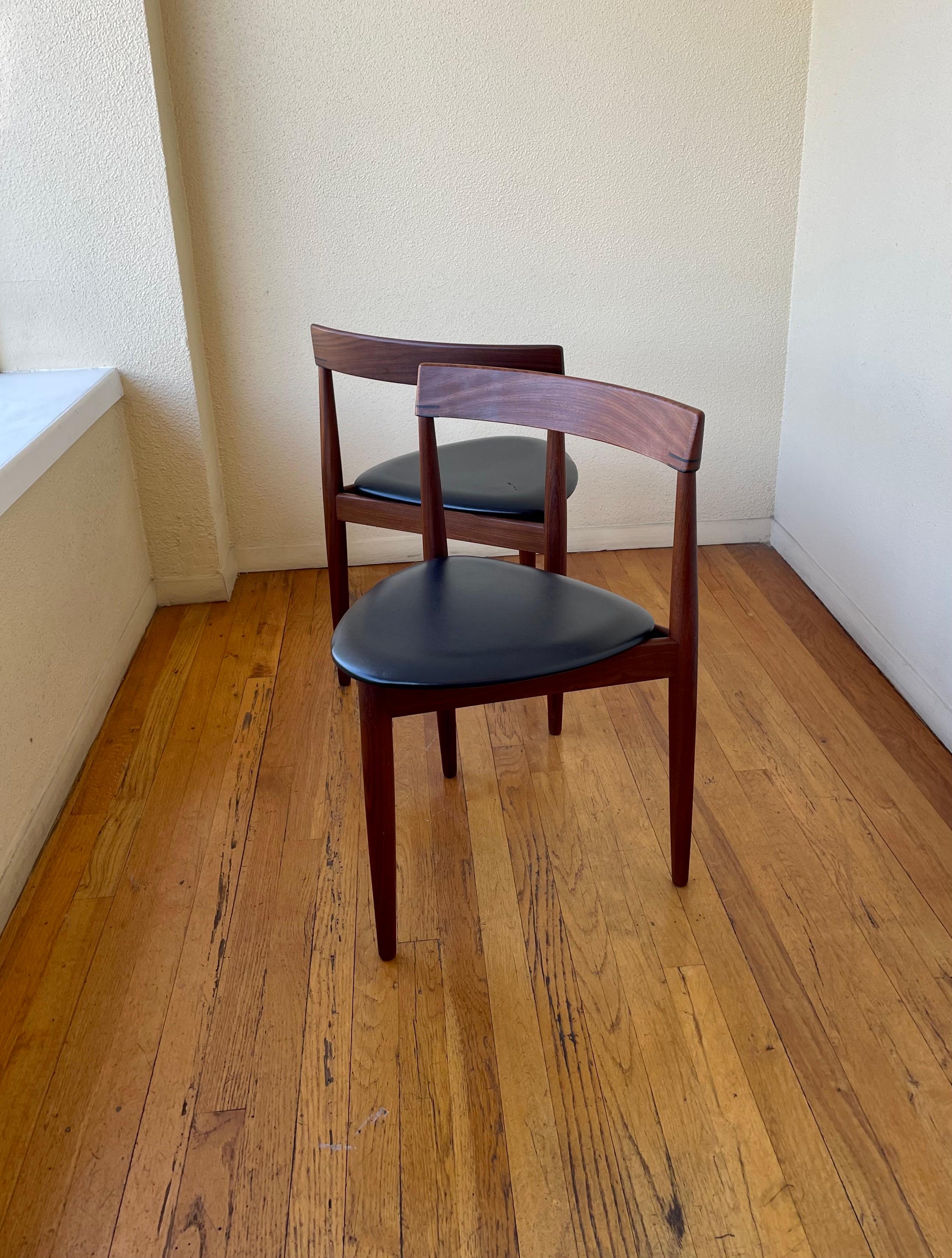 Pair of Danish modern, dining chairs by Hans Olsen for Frem Rojle feature contoured dark teak frames with 3 legs and Naugahyde, triangular seats.