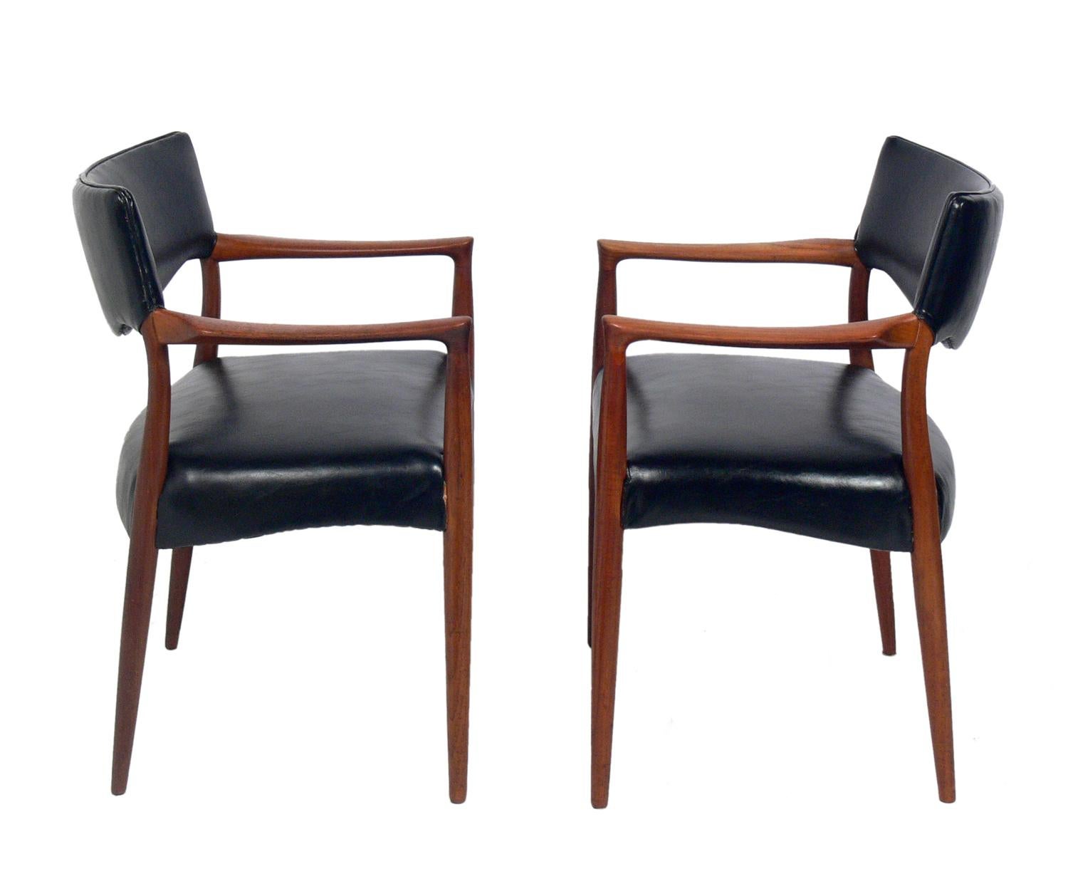 Pair of Danish modern chairs in the manner of Hans Wegner, Denmark, circa 1960s. They retain their black vinyl upholstery and have been cleaned and Danish oiled.