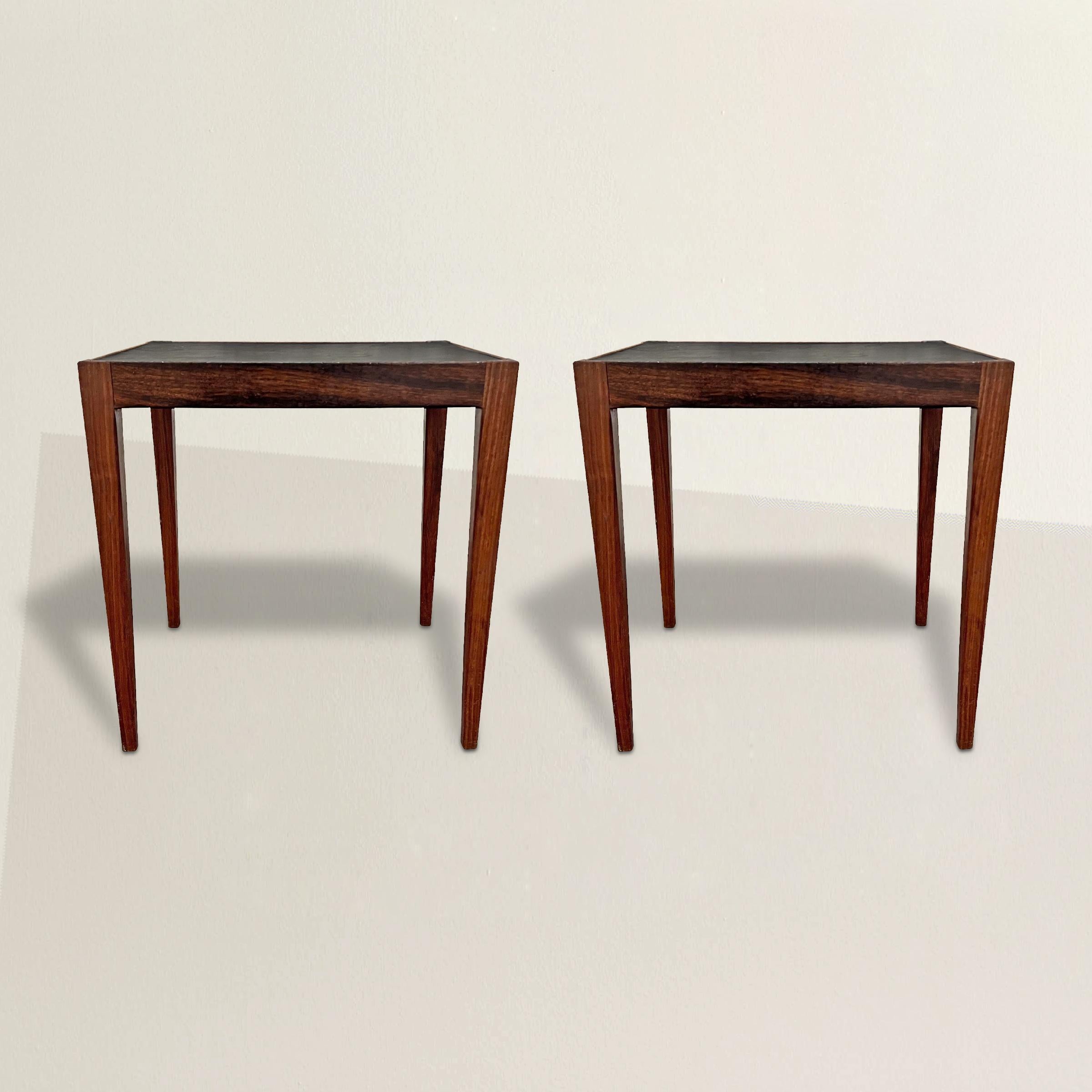 A stylish and straightforward pair of Danish Modern rosewood end tables with square tapered legs and black composition tops framed with a low beaded rim. From the famed Copenhagen department store, Illums Bolighus, marked under each top. The perfect