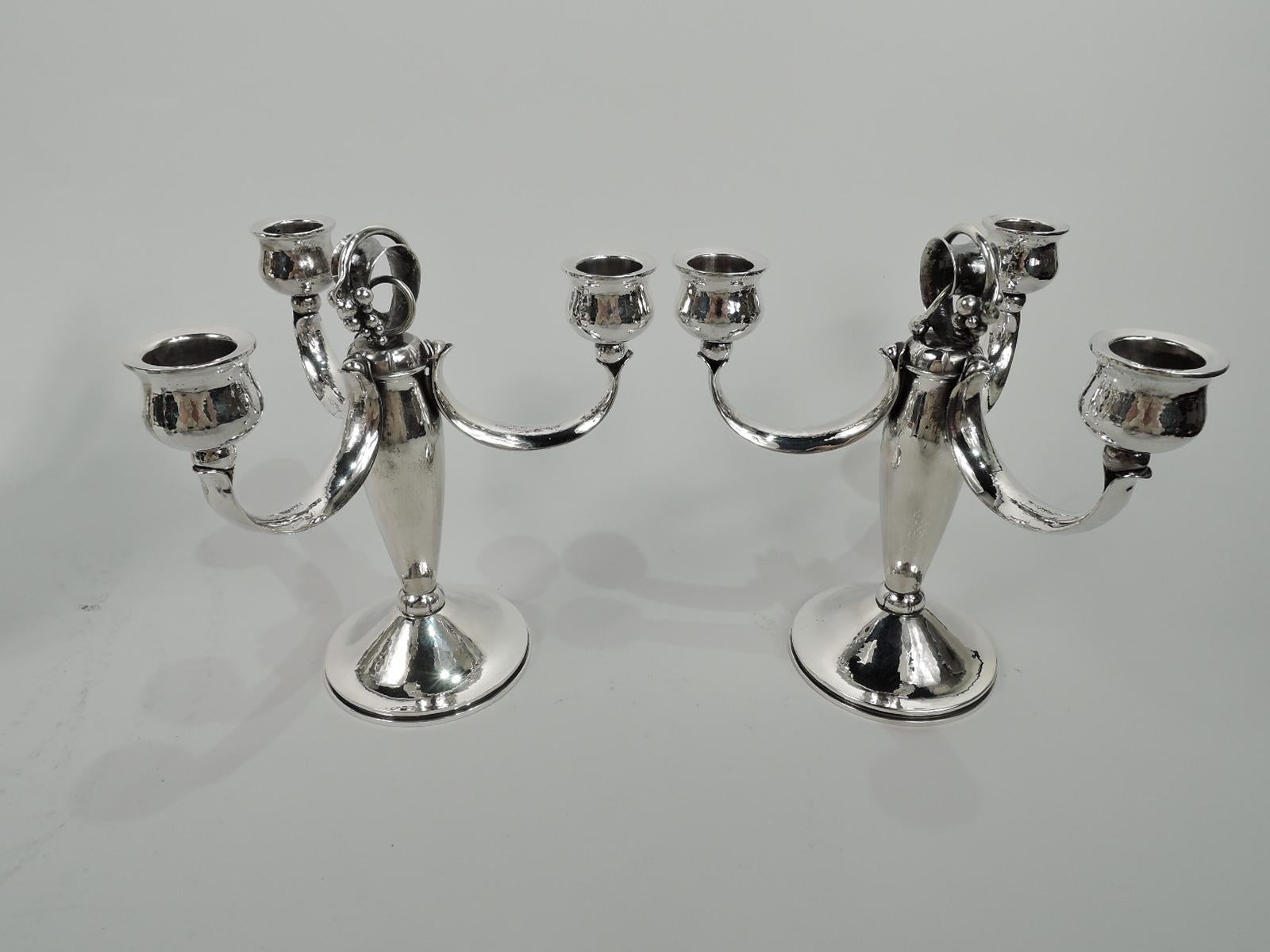 Pair of Danish Mid-Century Modern sterling silver 3-light candelabra. Each: Scroll encircled with fruiting grapevine mounted to tapering shaft with lobed knop at base mounted to raised and round foot. Three bud-mounted c-scroll arms, each