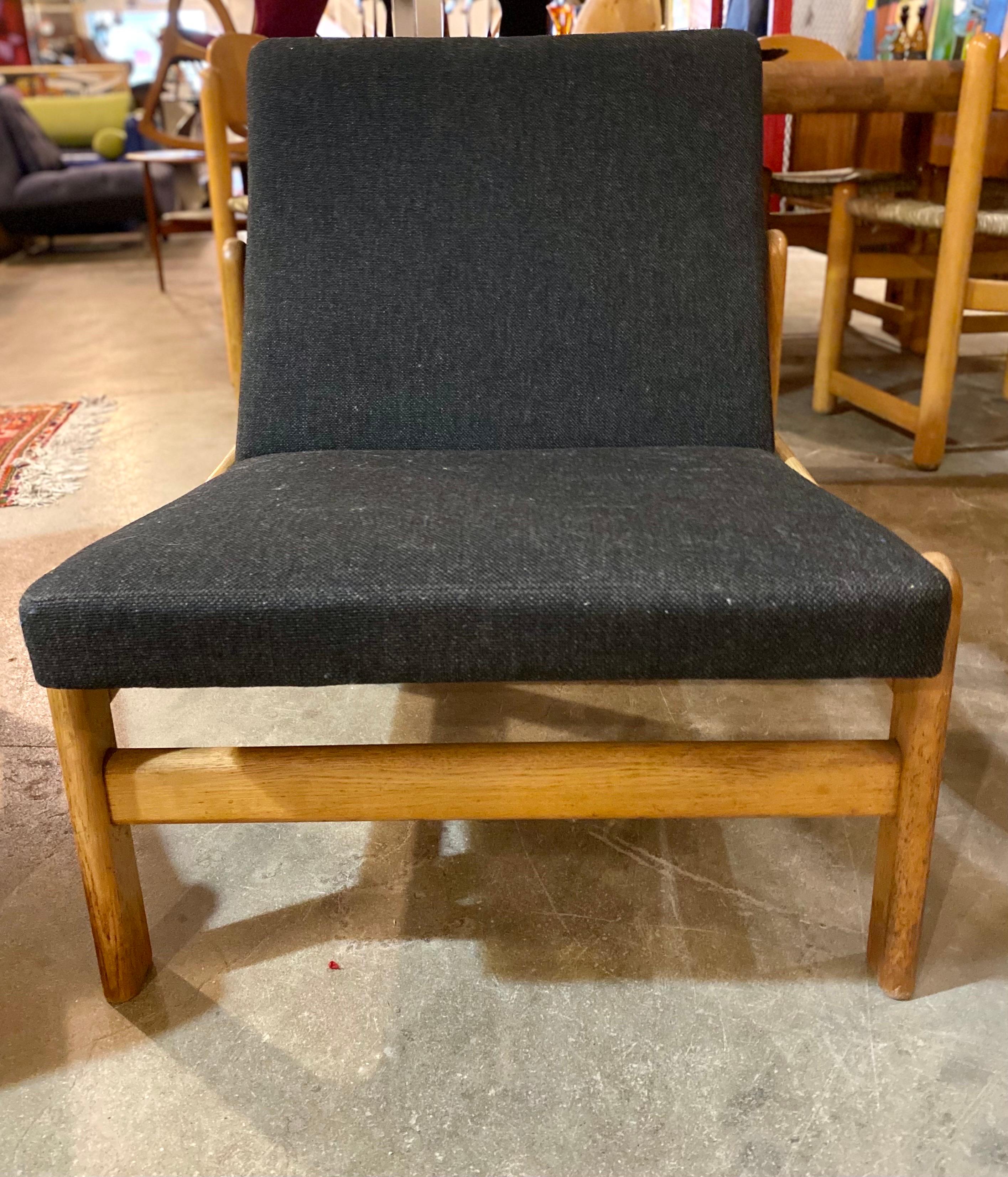 Pair of Danish modern Jørgen Bækmark chairs made of oak, circa 1960s feature dark grey almost black fabric and sit low. This pair of vintage chairs are in good overall condition. Measurements: 25” width x 29” height x 19” seat depth x 15” seat