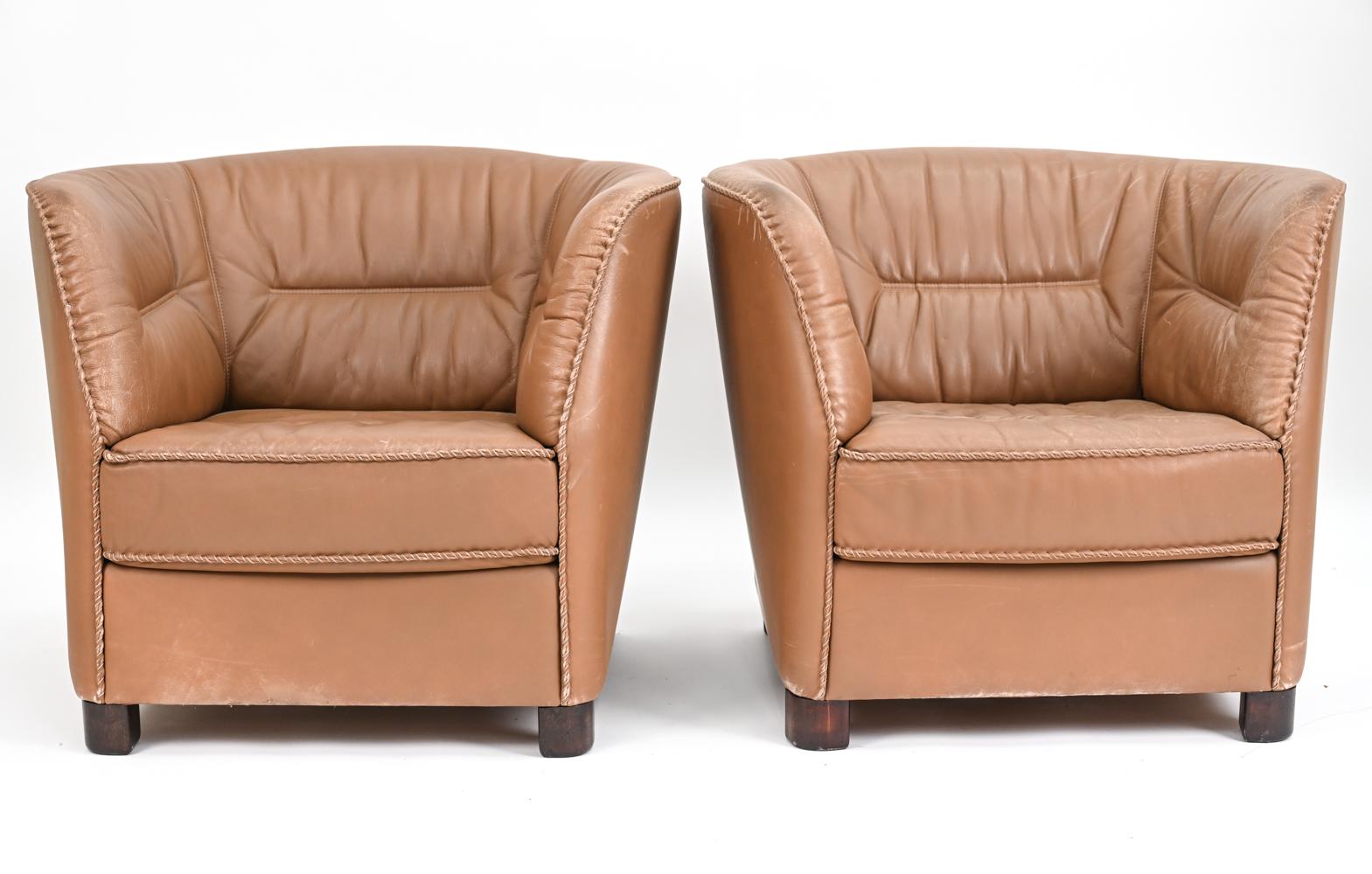 An unusual pair of Danish mid-century lounge chairs upholstered in fine grain tawny leather with whipstitch trim, featuring dark stained beechwood legs. These chairs, produced by Berg Furniture, c. 1970's, are both highly comfortable and