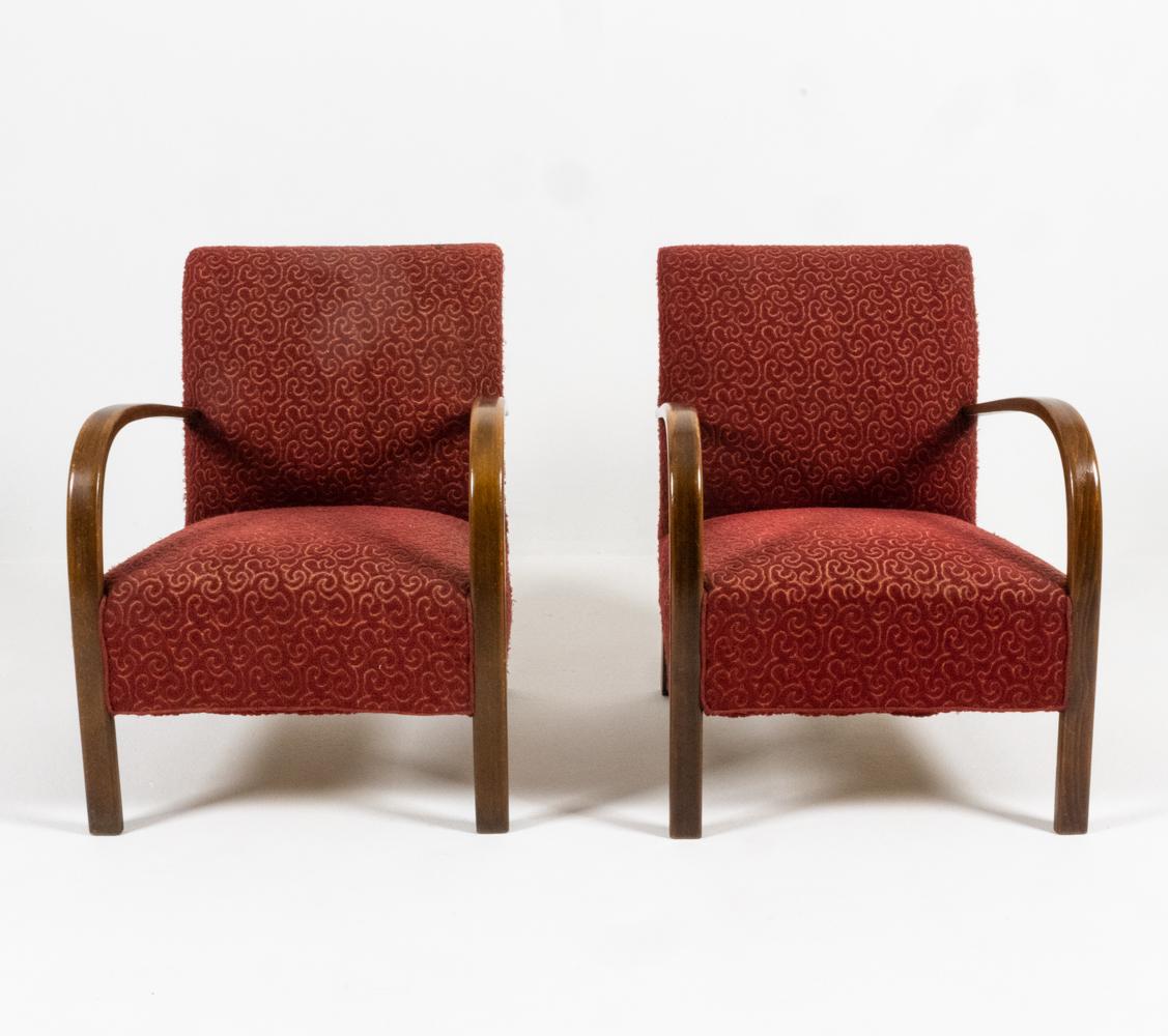 Poised at the transition between the eras of Art Deco and Modern design, this fabulous pair of armchairs by Fritz Hansen features dramatic sculpted beechwood arms in a dark, oaky stain. The substantial seat and backrest are finished in